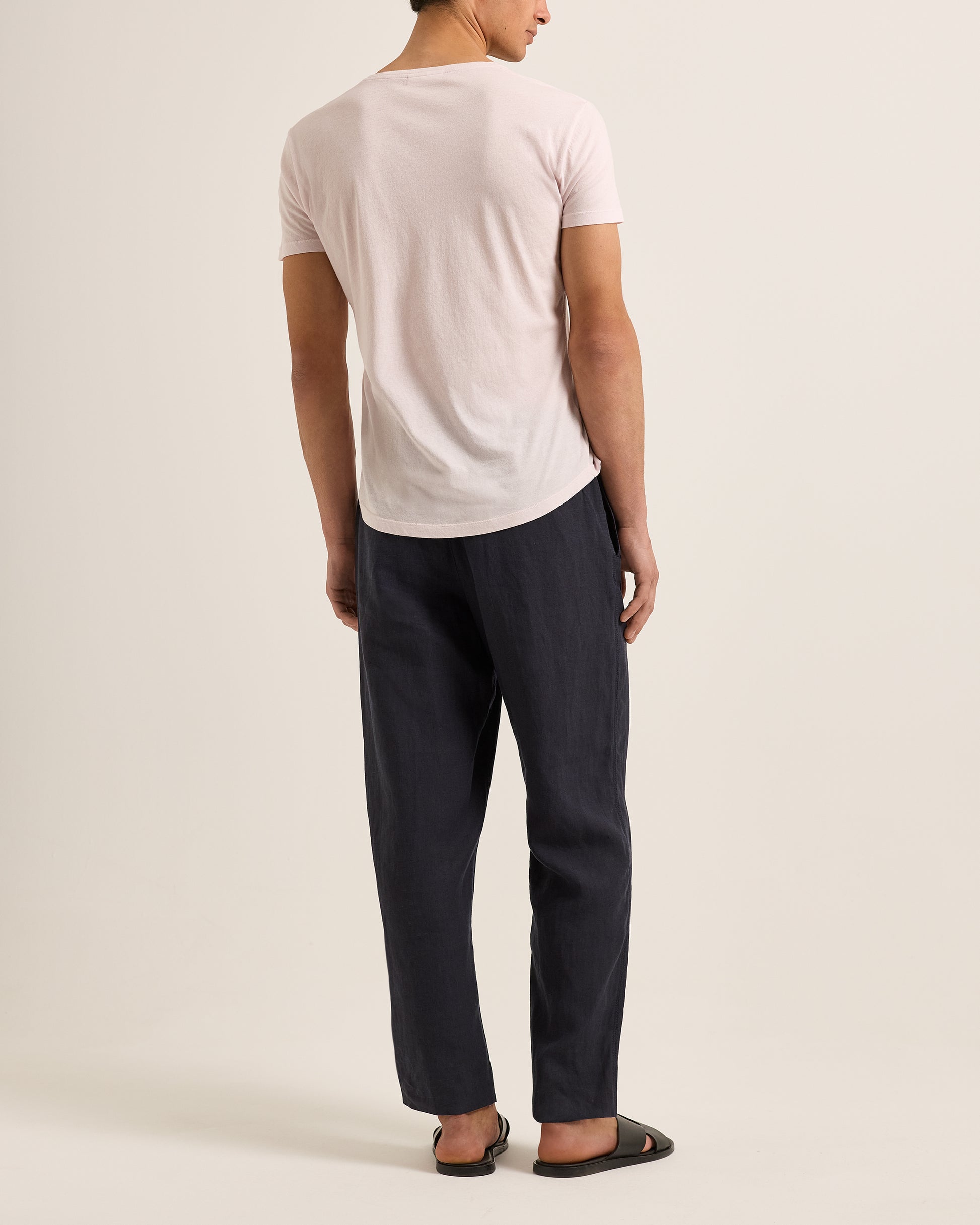 Person wearing a white t-shirt and dark pants on a plain background