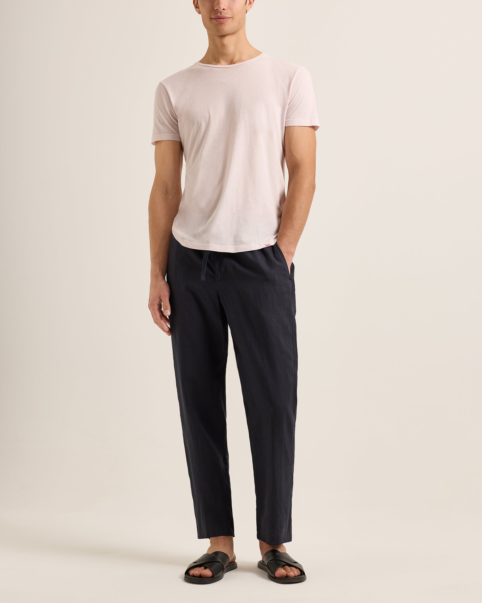 Person wearing a light pink t-shirt and black pants on a plain background