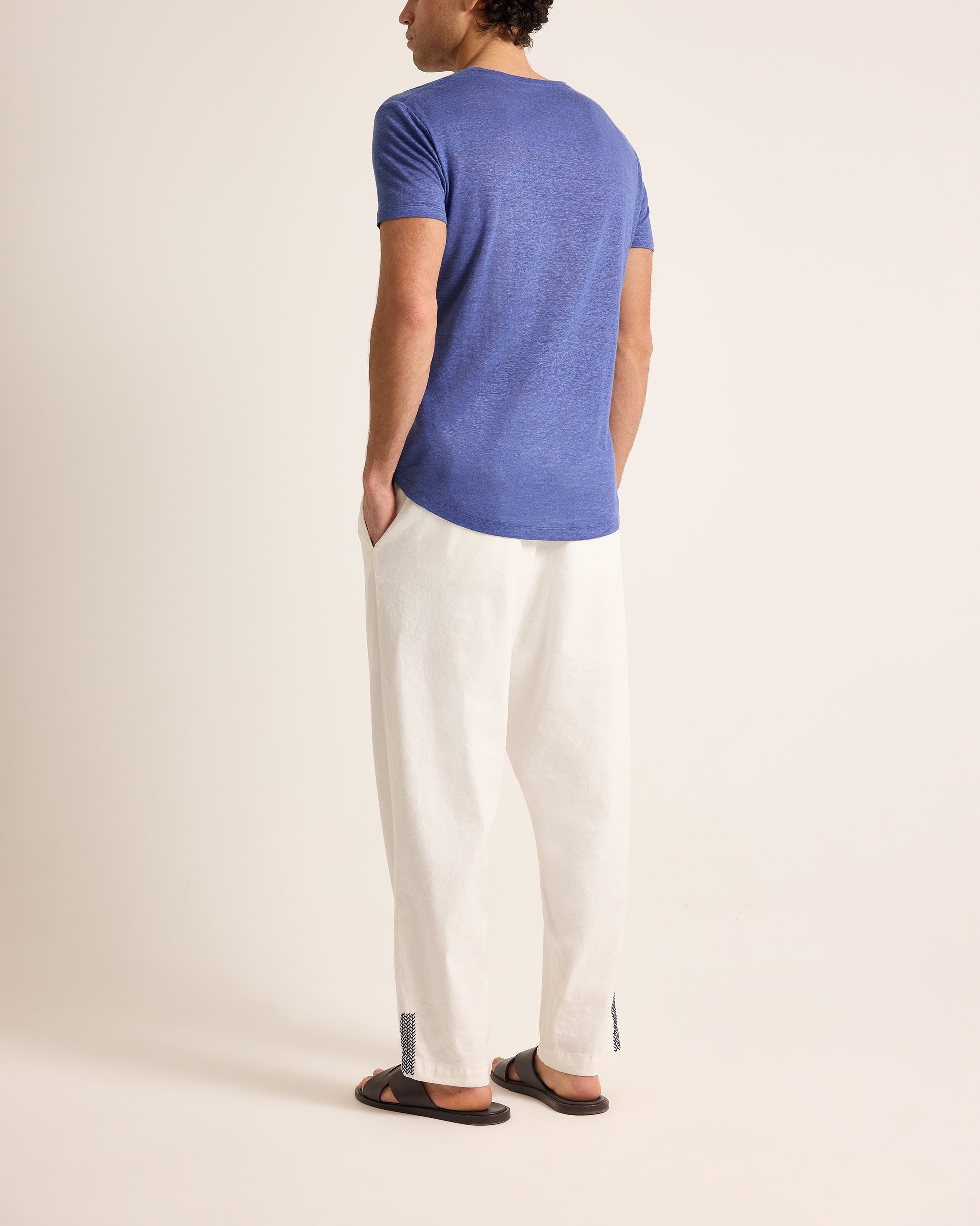 Person wearing a blue t-shirt and white pants on a plain background