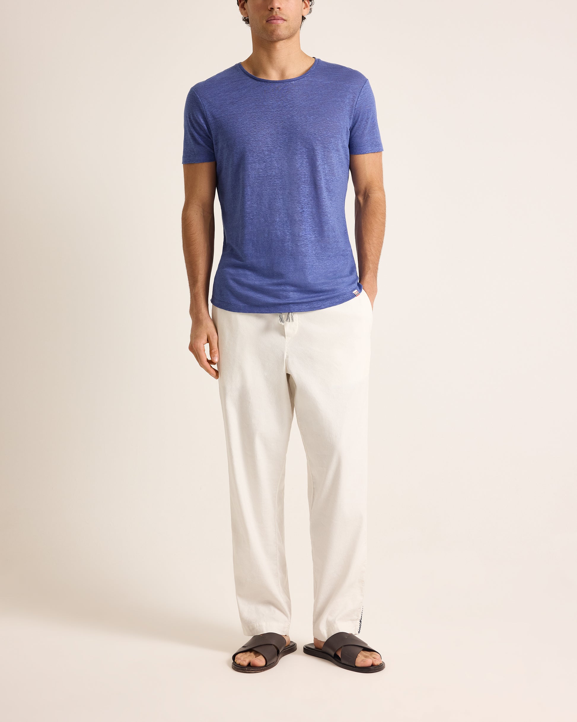 Person wearing a blue t-shirt and white pants on a plain background