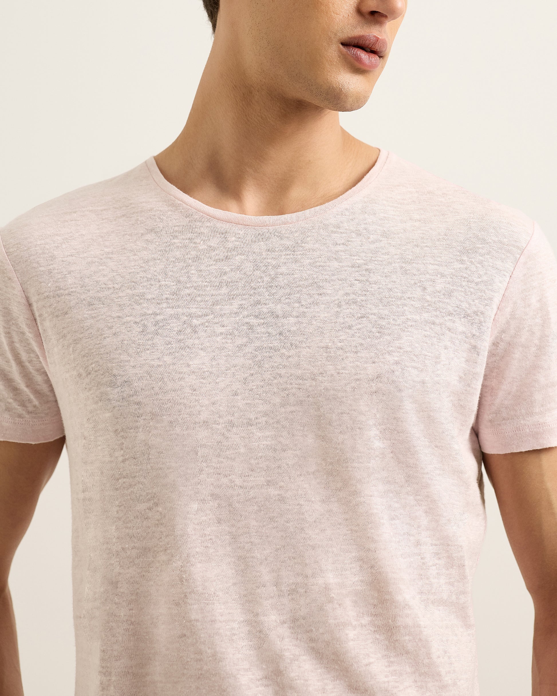Man wearing a light pink t-shirt against a plain background