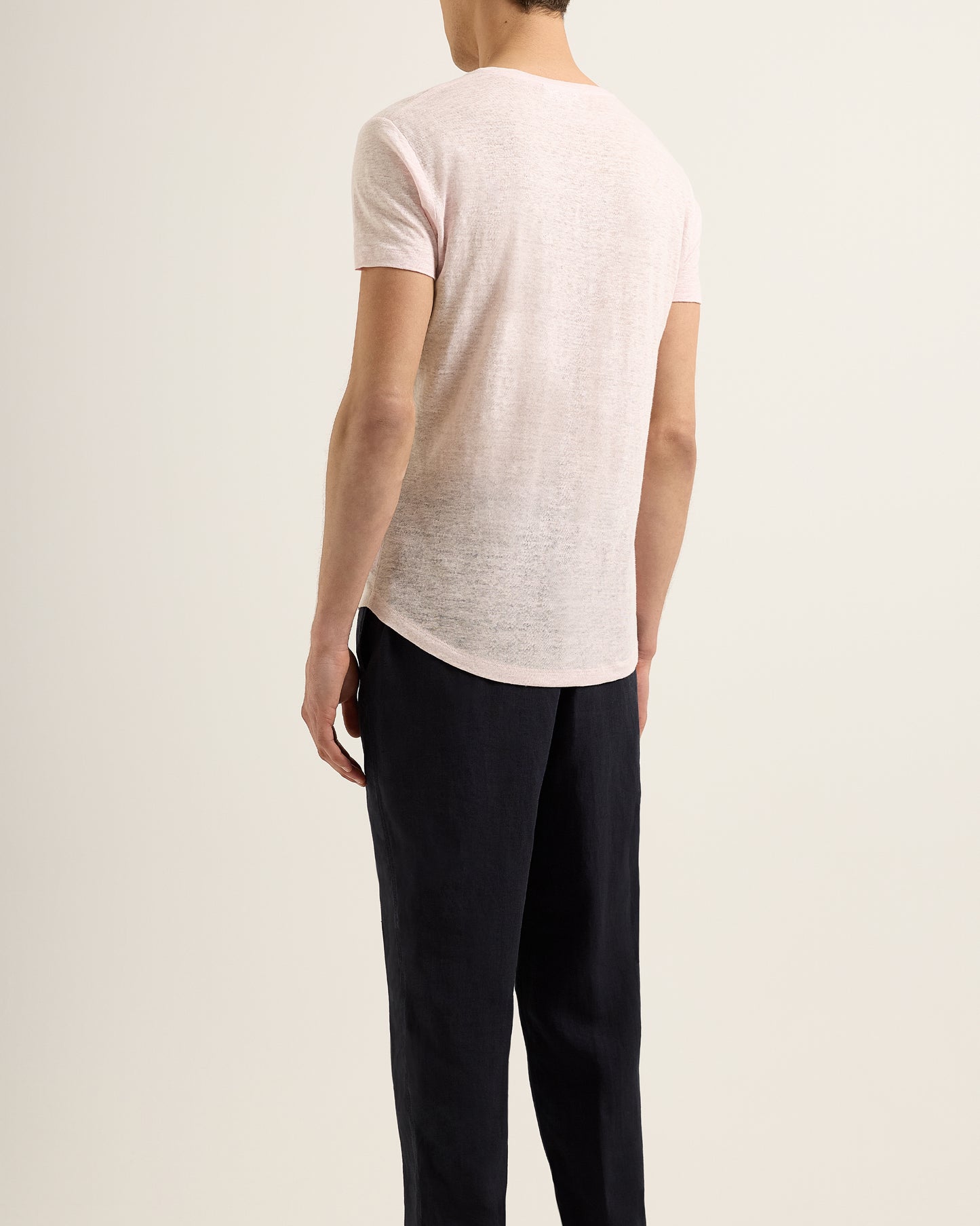 Person wearing a light pink t-shirt and black pants on a plain background