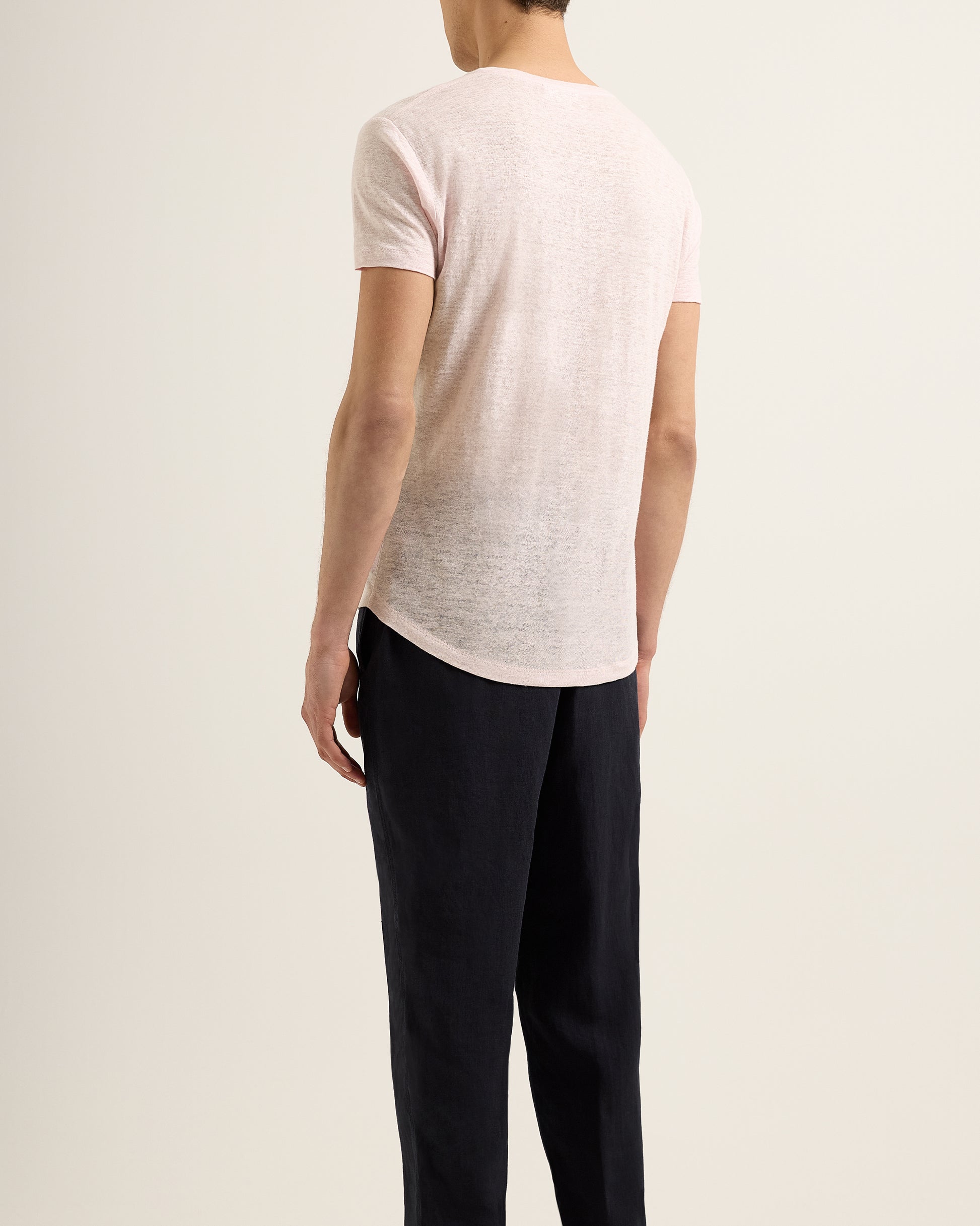 Person wearing a light pink t-shirt and black pants on a plain background