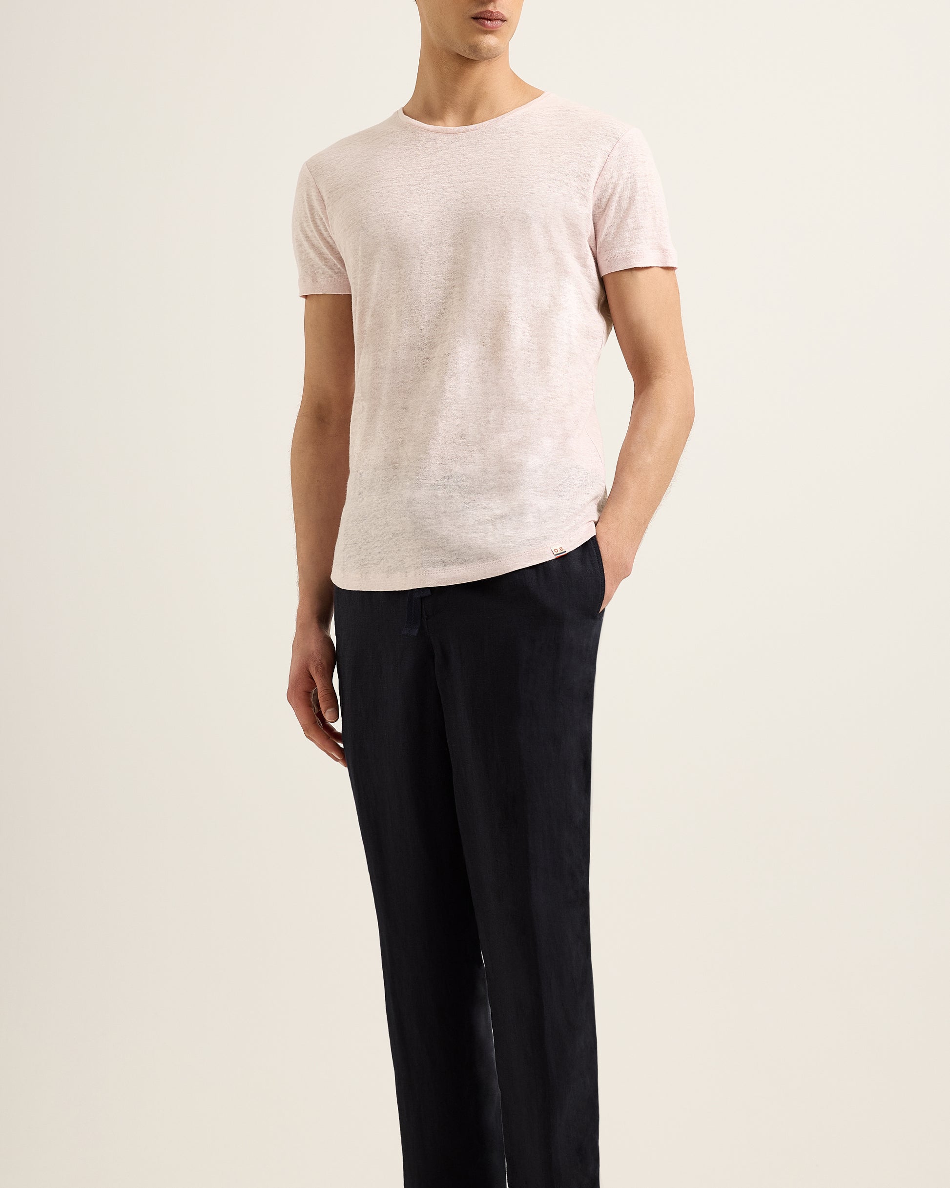 Man wearing light ink t-shirt with black trousers on a beige background