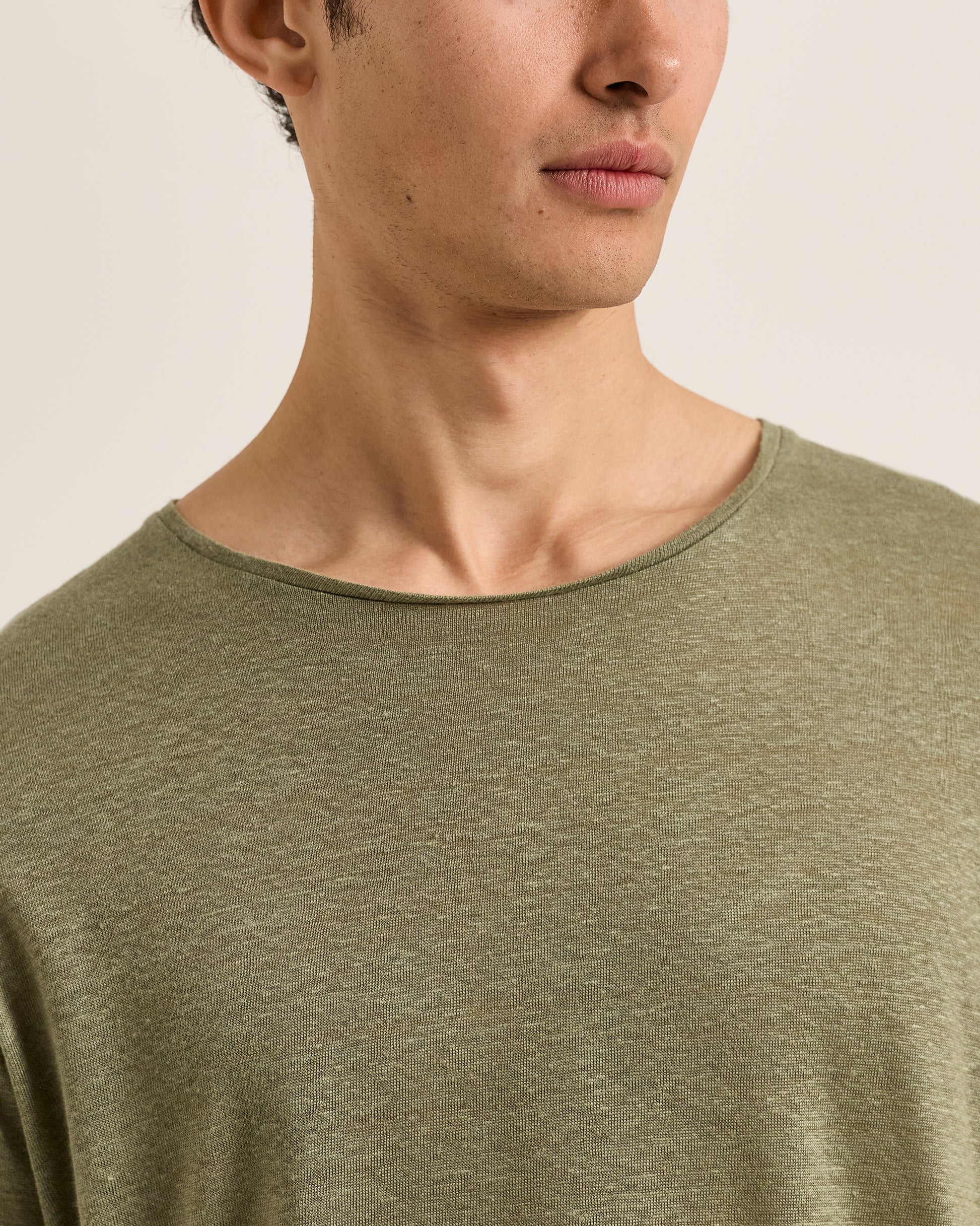Close-up of a person wearing an olive green shirt against a plain background