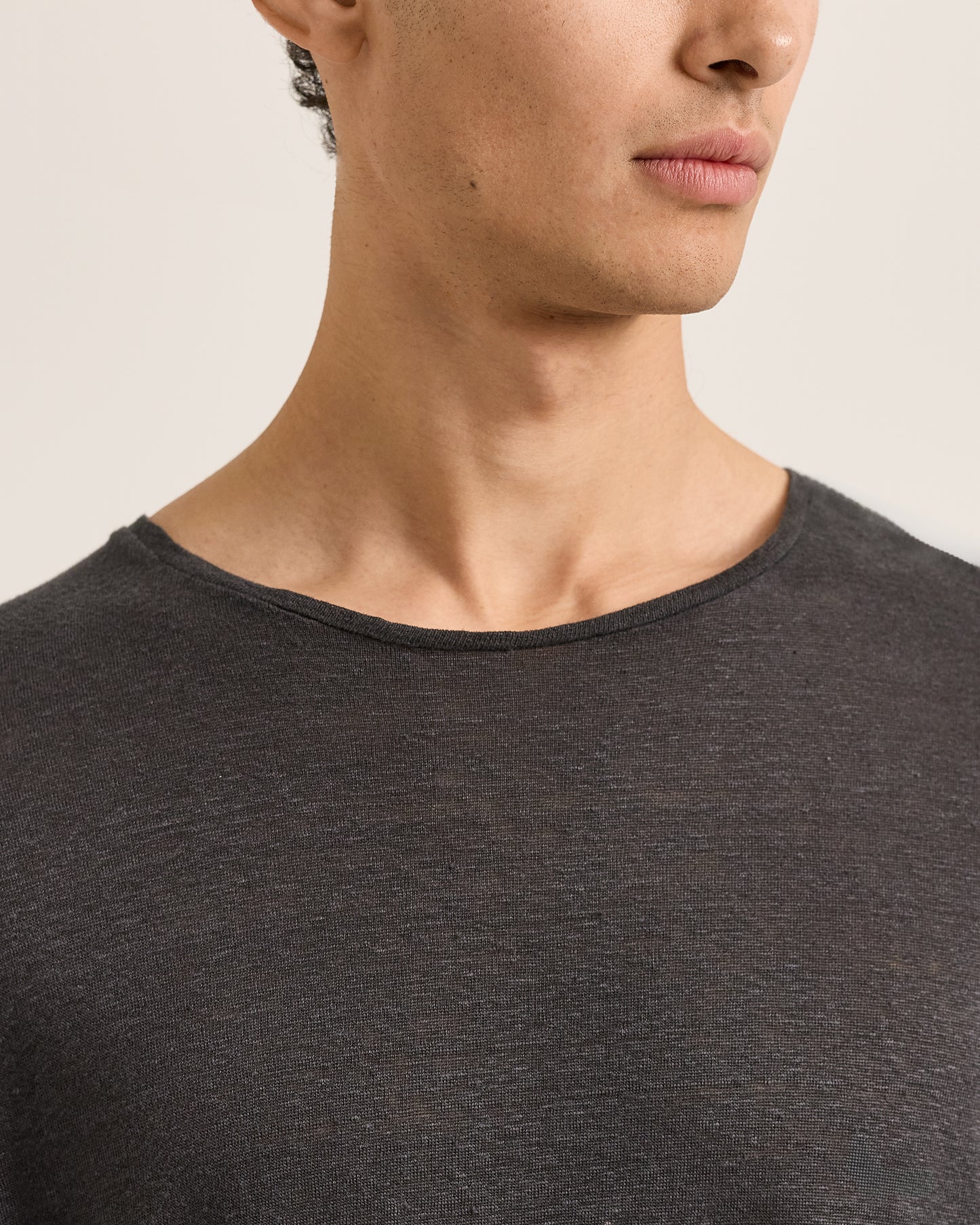 Close-up of a person wearing a dark gray shirt against a neutral background