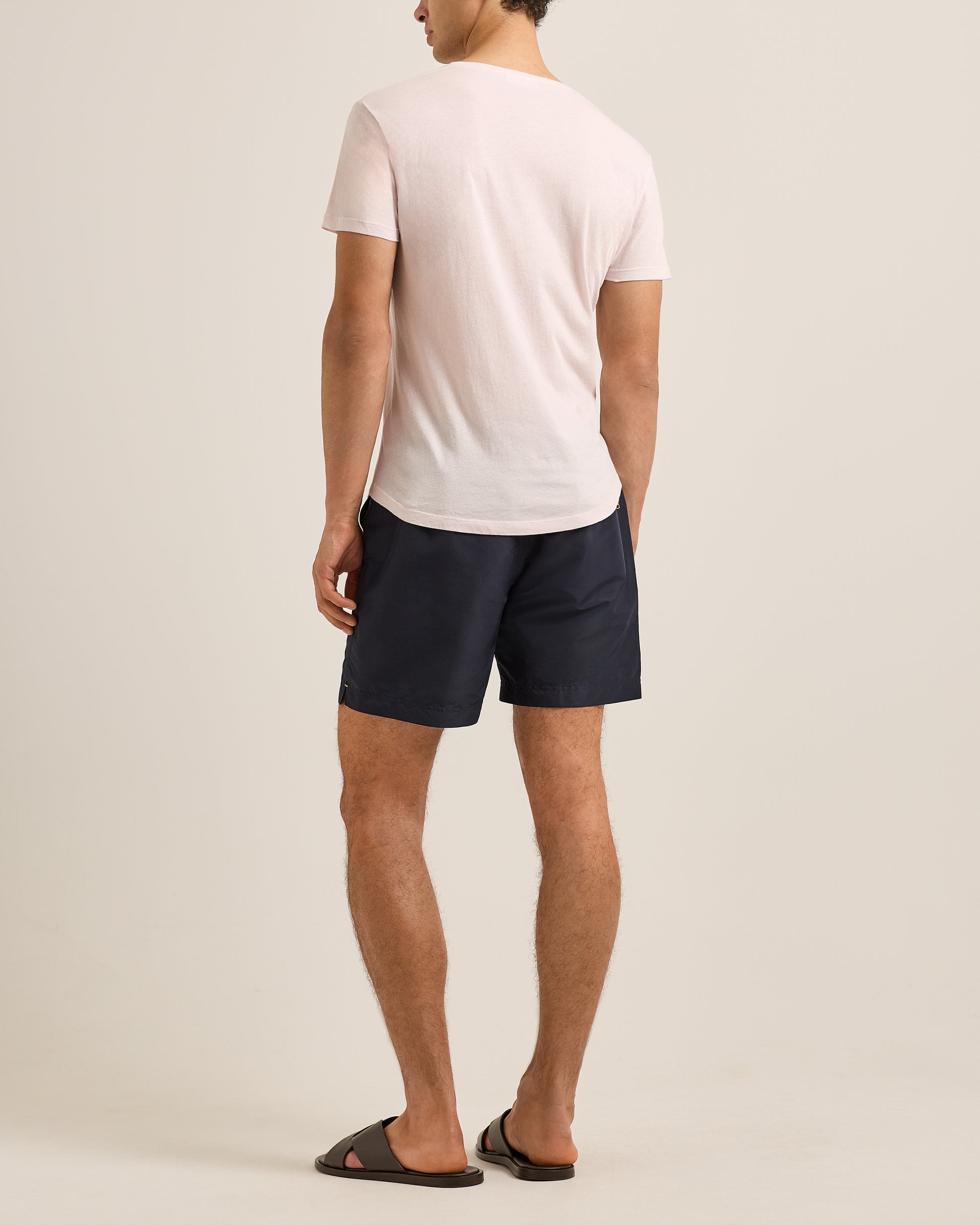 Person wearing navy shorts and a white t-shirt on a plain background