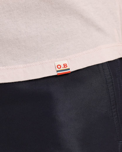 Close-up of a label with 'O.B.' on a garment with a light gray top and dark fabric.