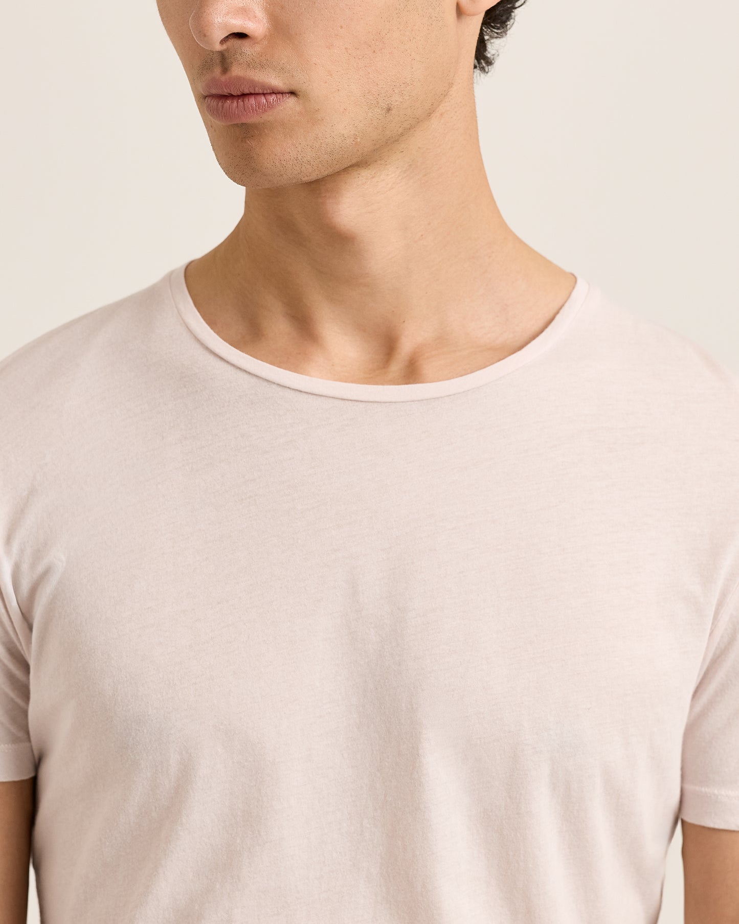Man wearing a beige t-shirt against a neutral background