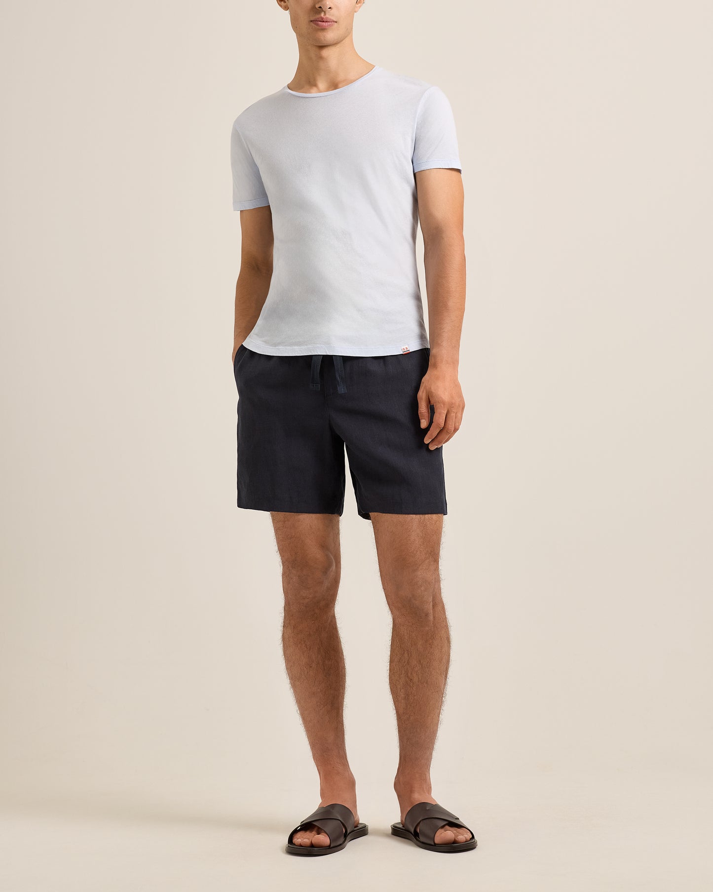 Person wearing a light blue t-shirt and black shorts on a beige background