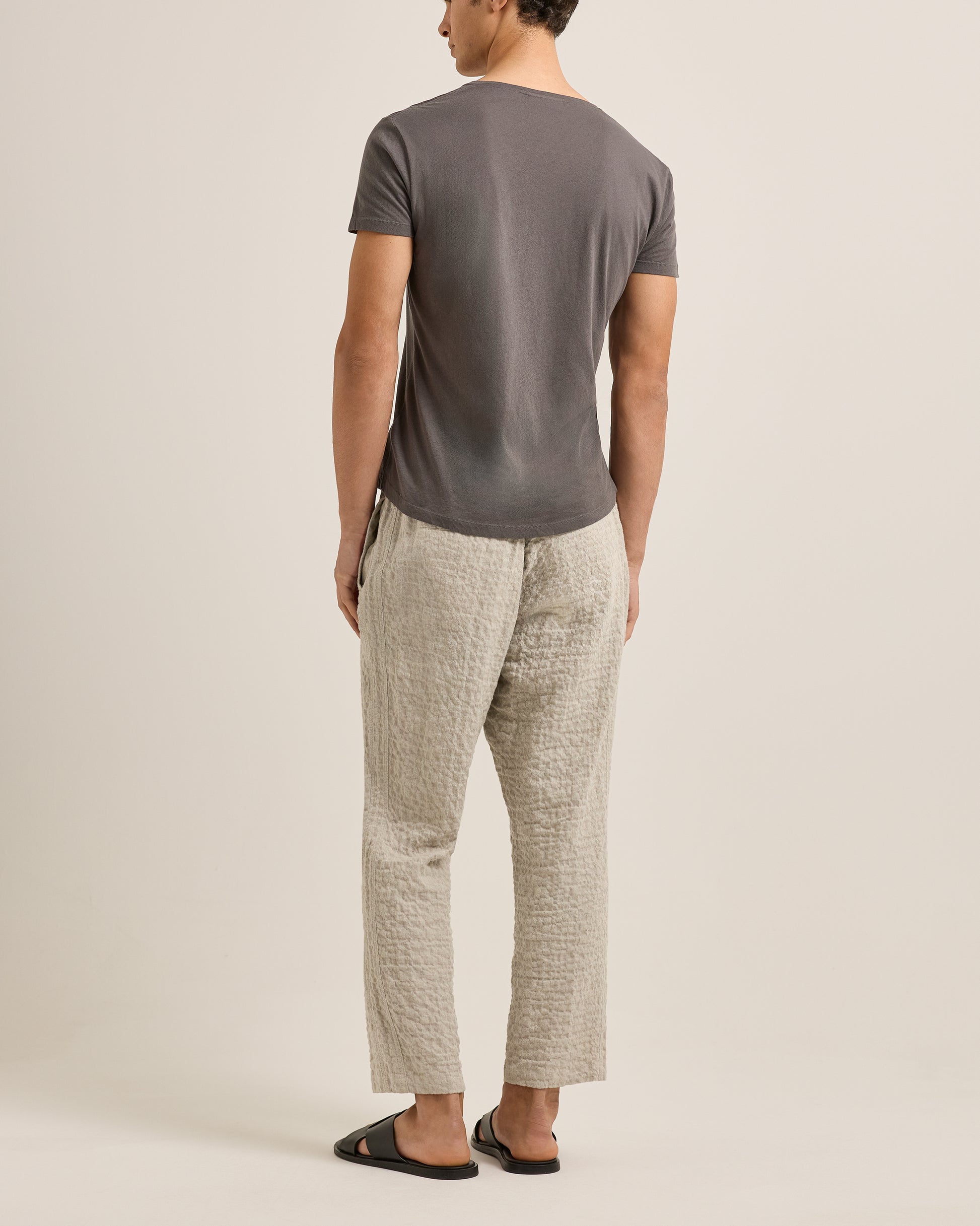 Man wearing a gray t-shirt and light-colored pants on a beige background