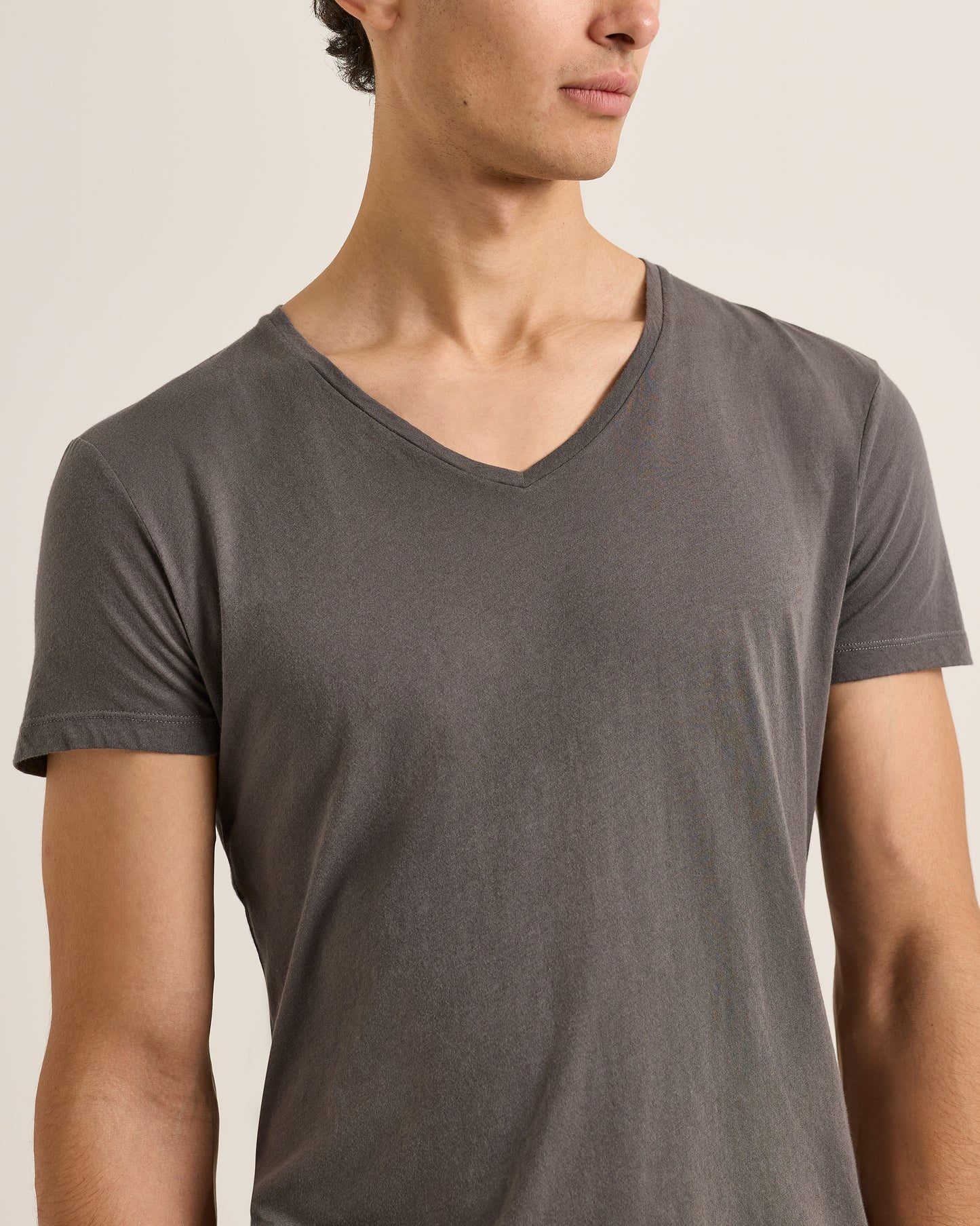 Man wearing a plain gray t-shirt against a neutral background