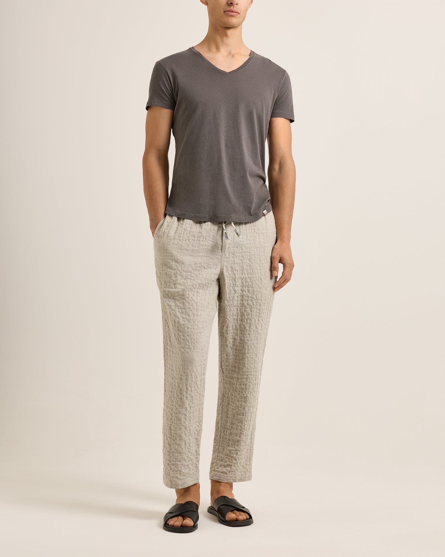 Person wearing a gray t-shirt and beige pants on a plain background