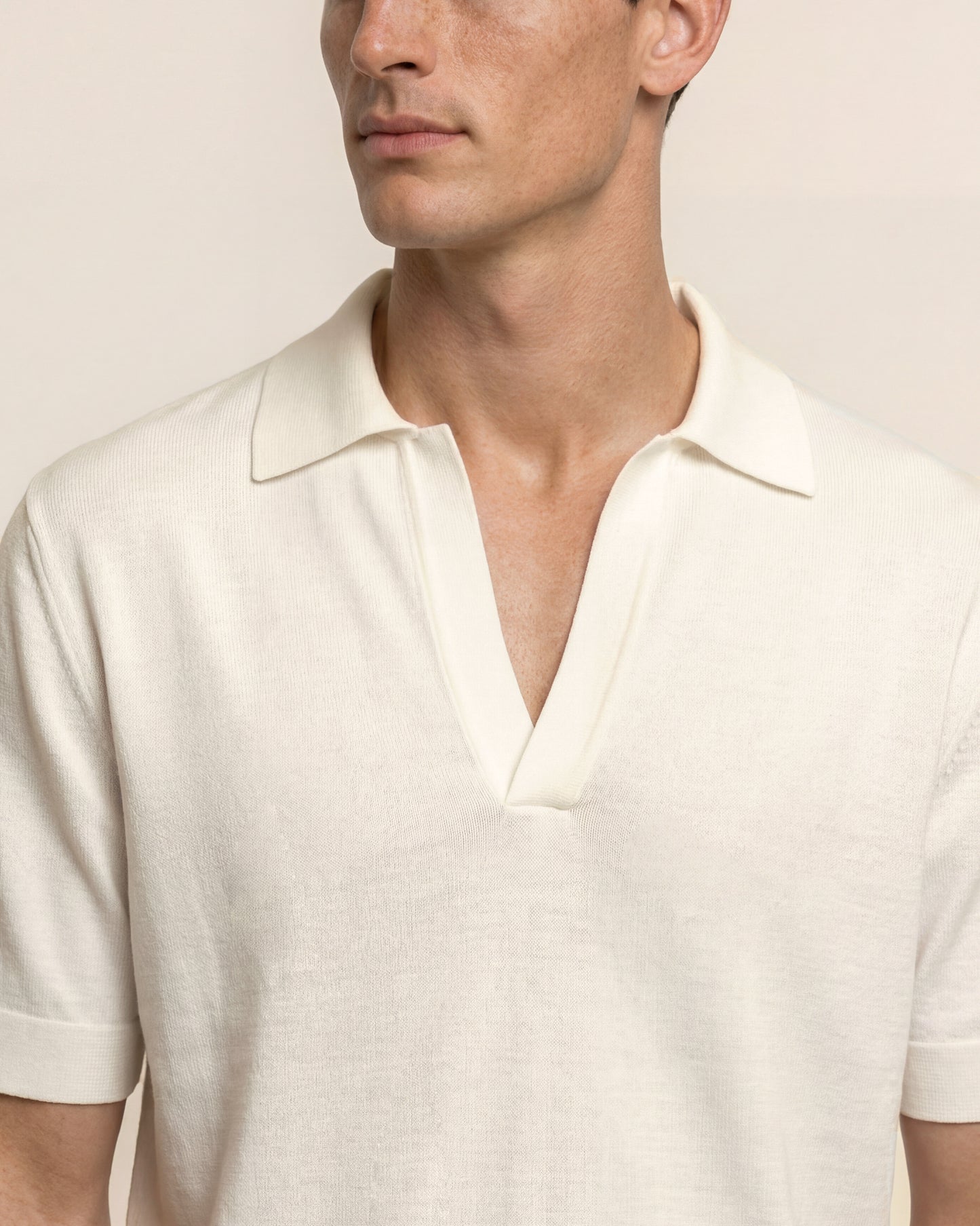 Man wearing a white polo shirt against a neutral background