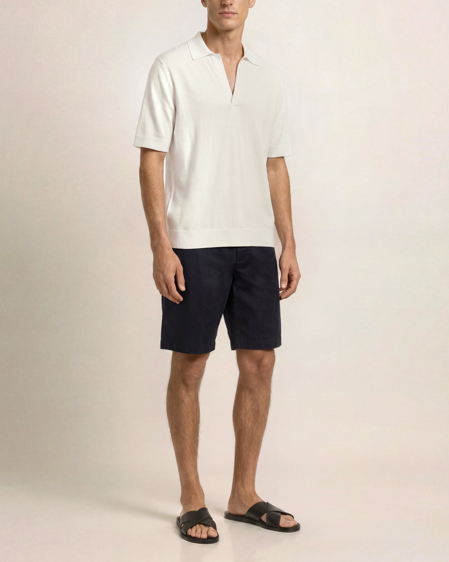 Man wearing a white shirt and black shorts on a plain background