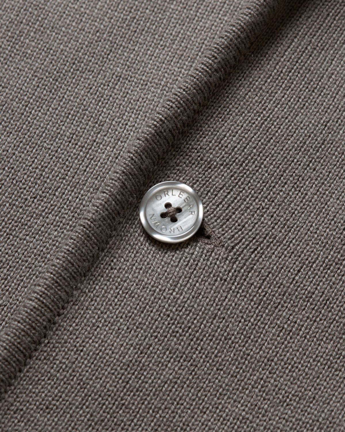 Close-up of a dark taupe knit fabric with a single silver button on the front.