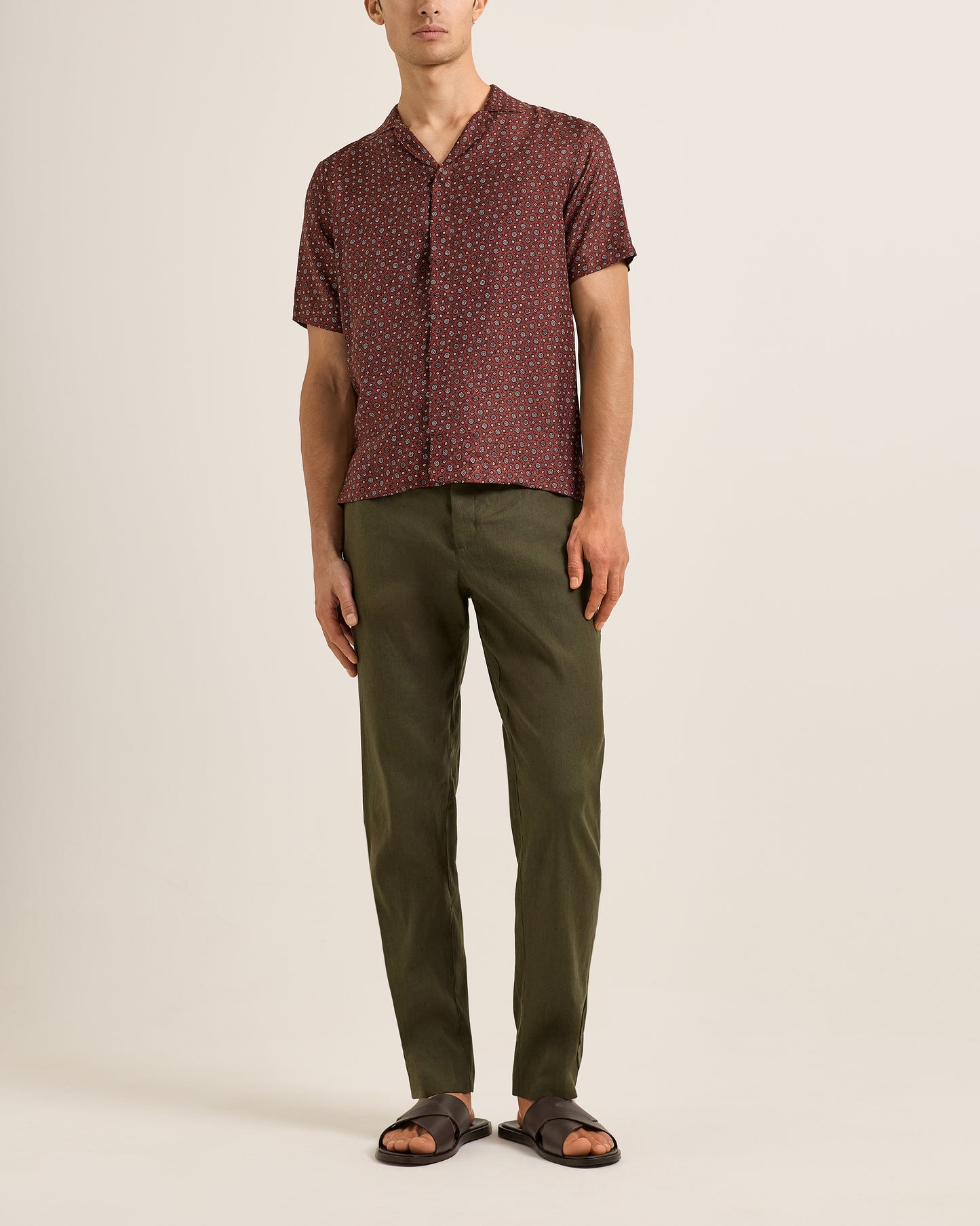 Man wearing a patterned shirt and Ray linen green pants on a beige background