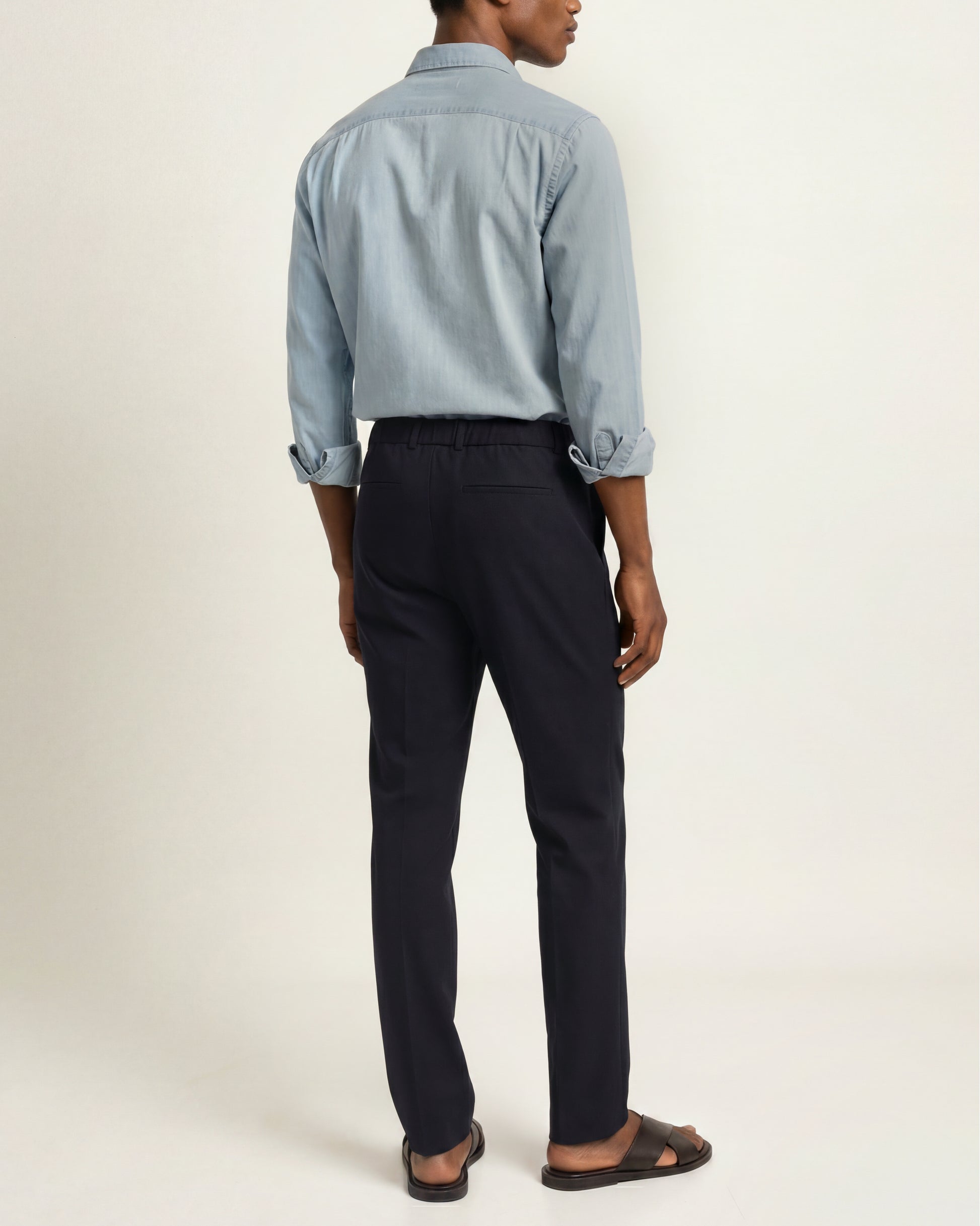 Back shot of a model wearing navy cotton trousers against a white background