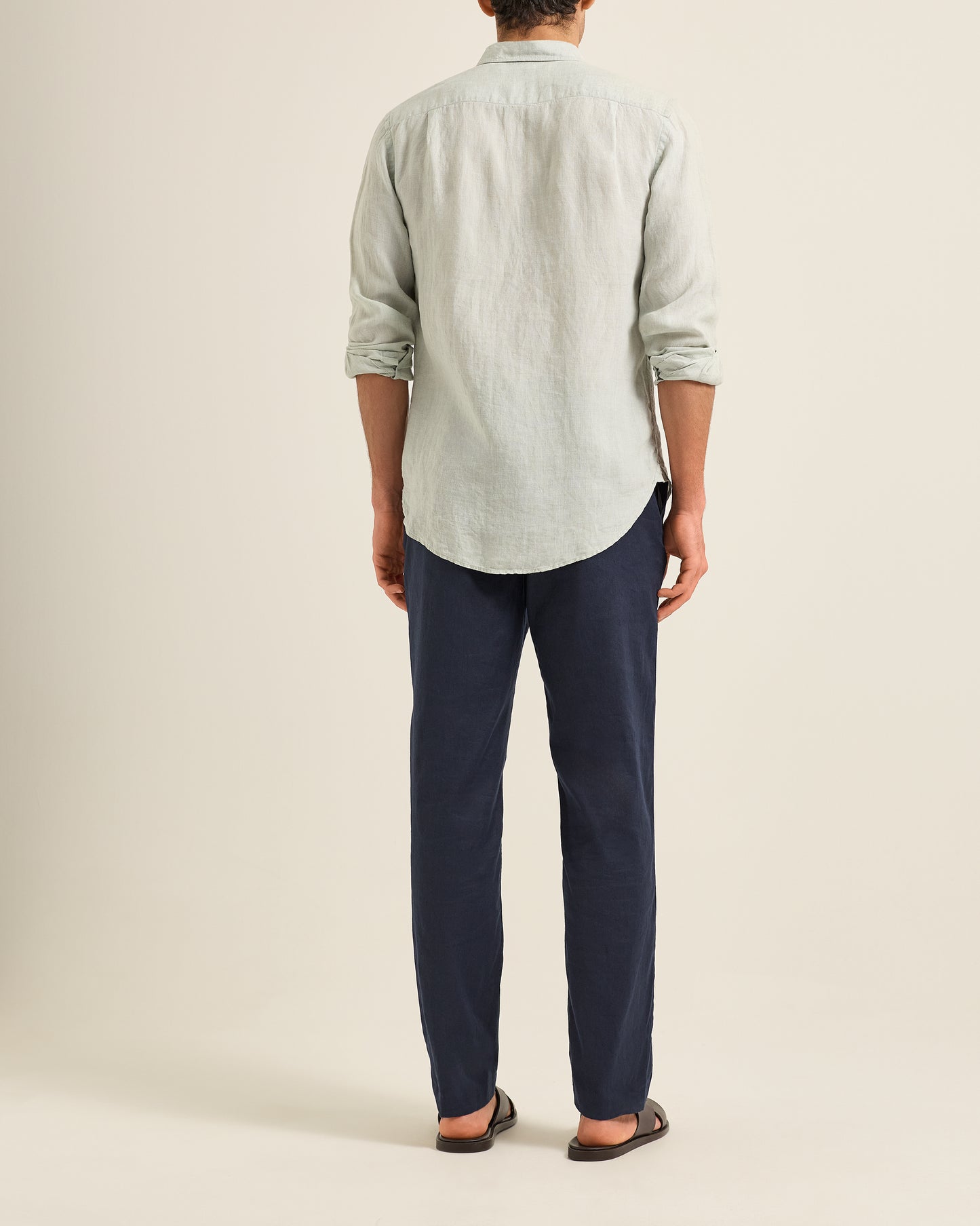 Person wearing a light green shirt and Ray linen navy tailored trousers on a beige background