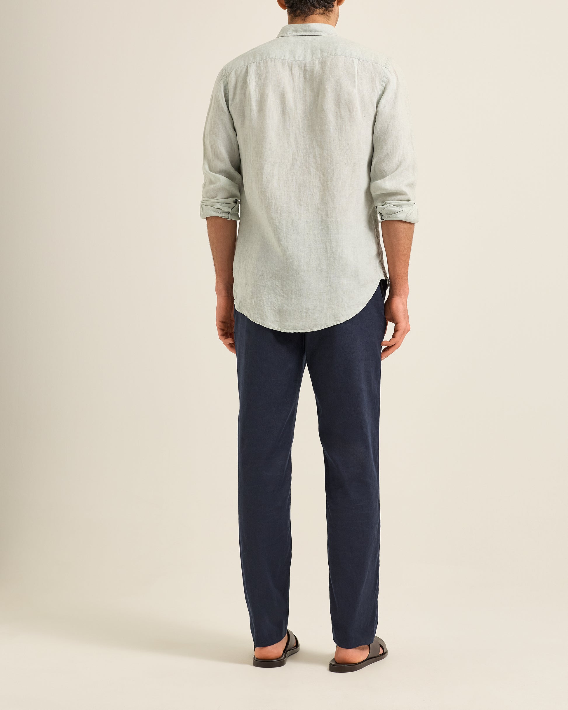 Person wearing a light green shirt and Ray linen navy tailored trousers on a beige background