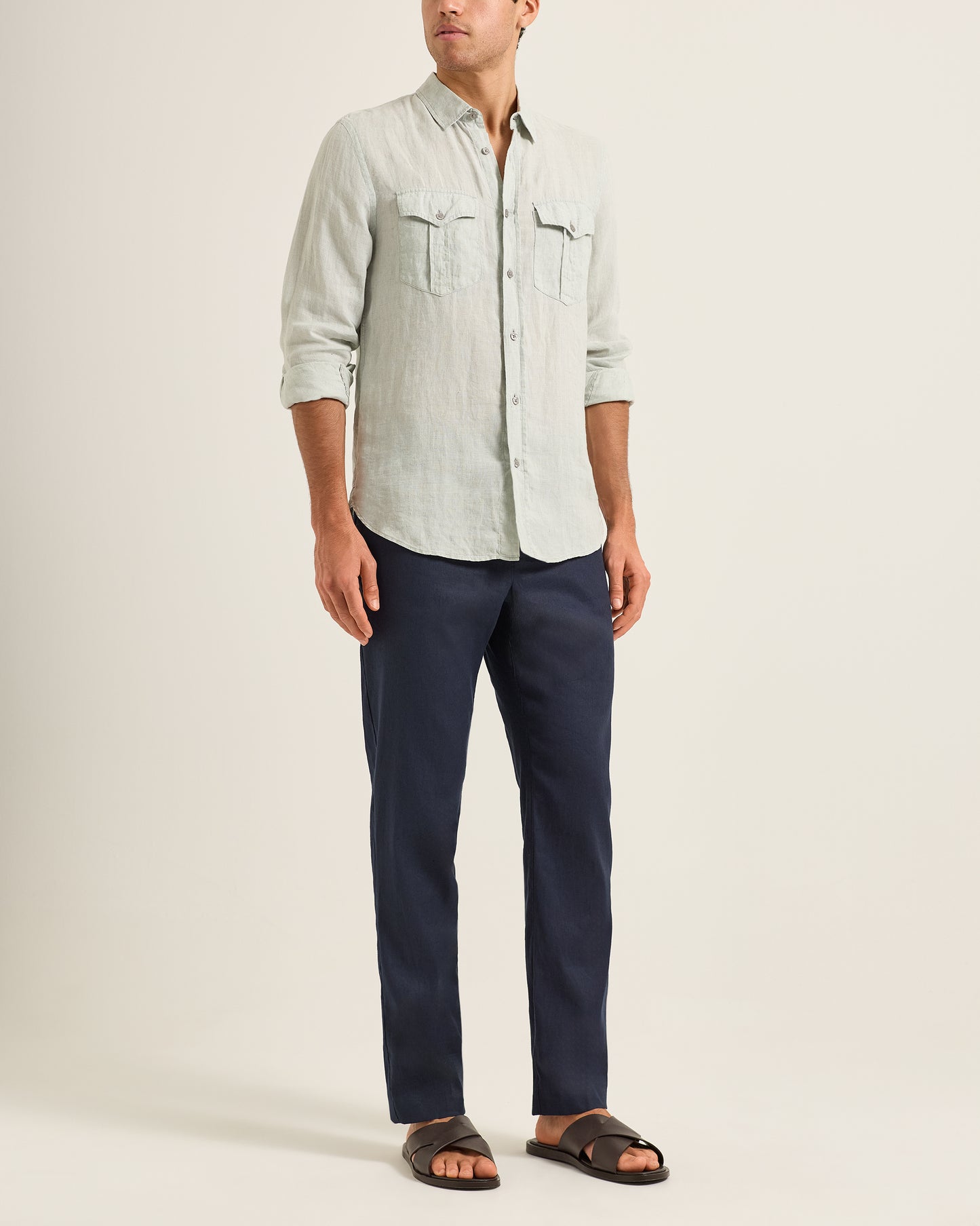 Man wearing a light gray shirt and Ray linen navy tailored trousers on a white background
