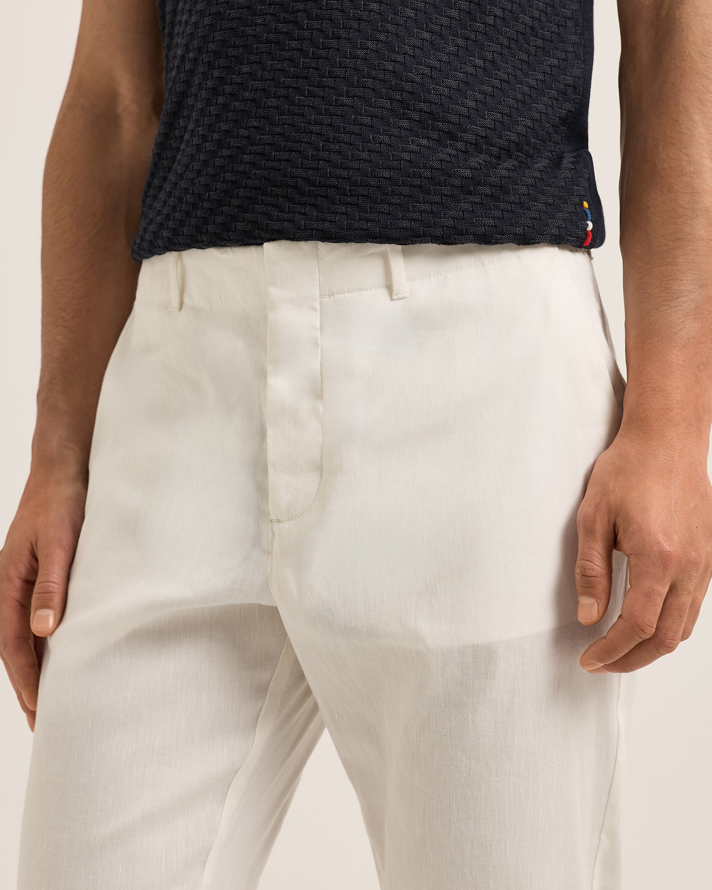 Person wearing a navy textured shirt and Ray linen tailored white trousers on a white background