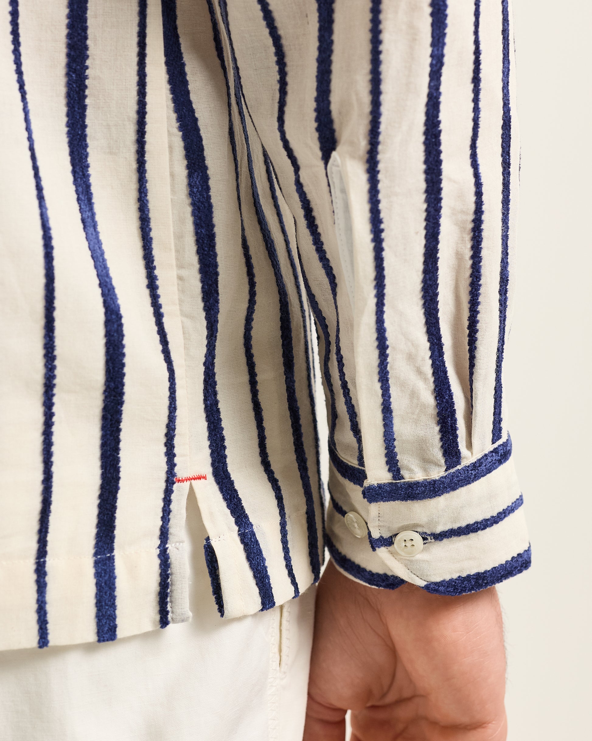 Close-up of a person wearing a white shirt with blue vertical stripes.