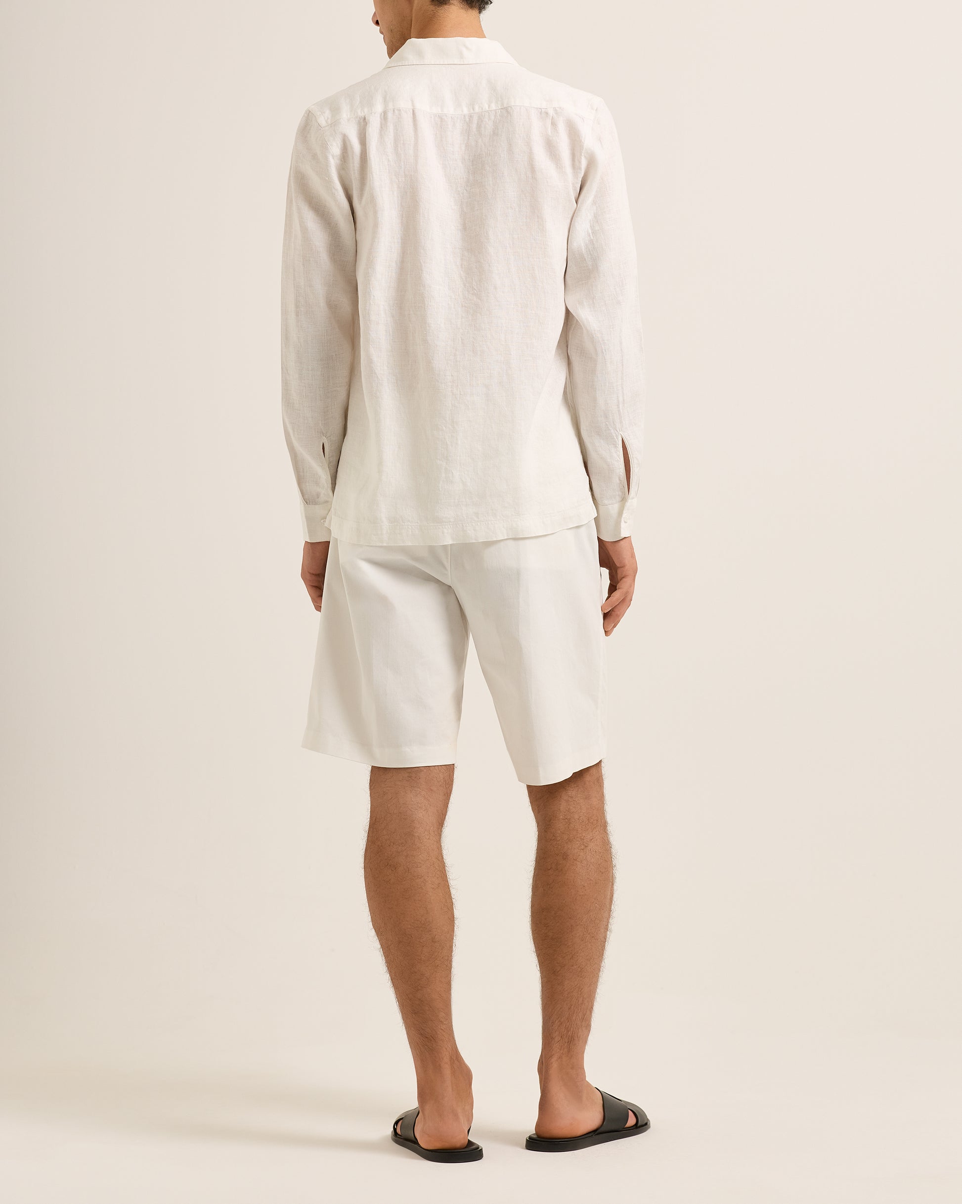 Person wearing a white outfit with shorts on a plain background