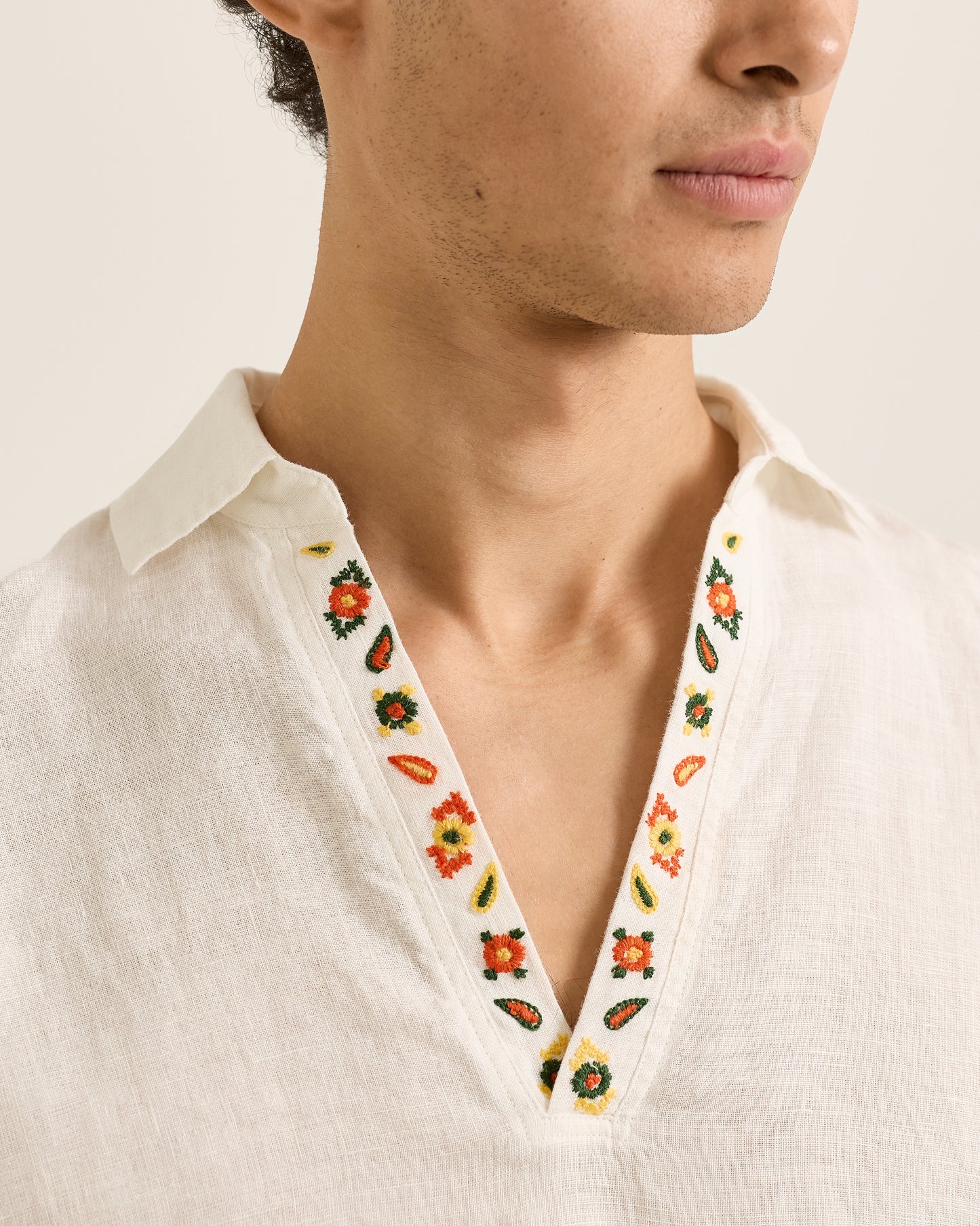Close-up of a person wearing a white shirt with floral embroidery on the collar.