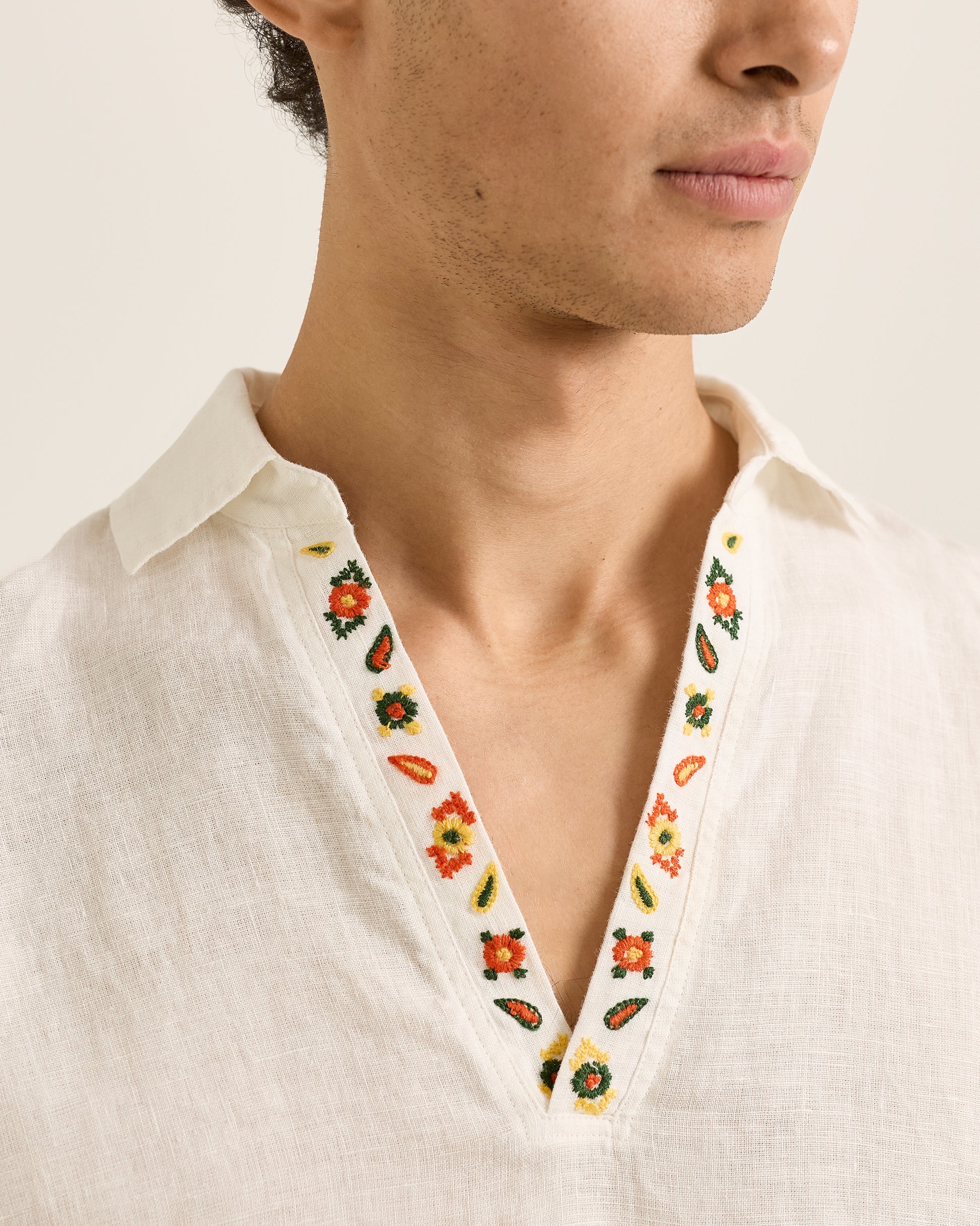 Close-up of a person wearing a white shirt with floral embroidery on the collar.