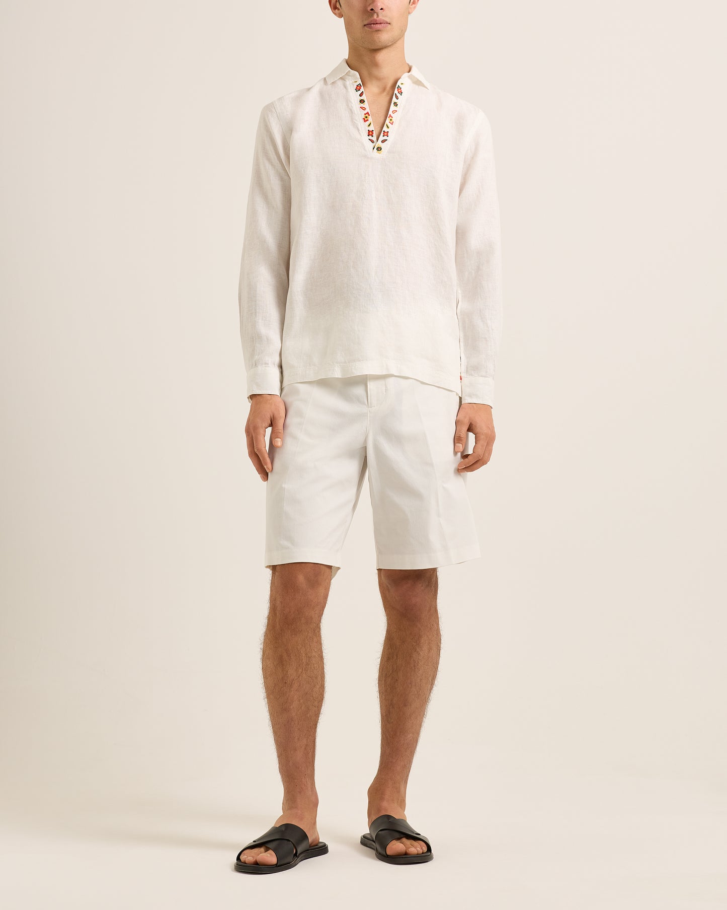 Man wearing a light-colored shirt and shorts on a plain background