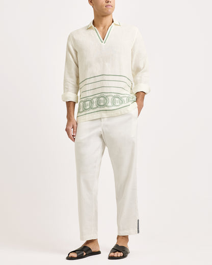 Person wearing a white embroidered shirt and pants on a white background