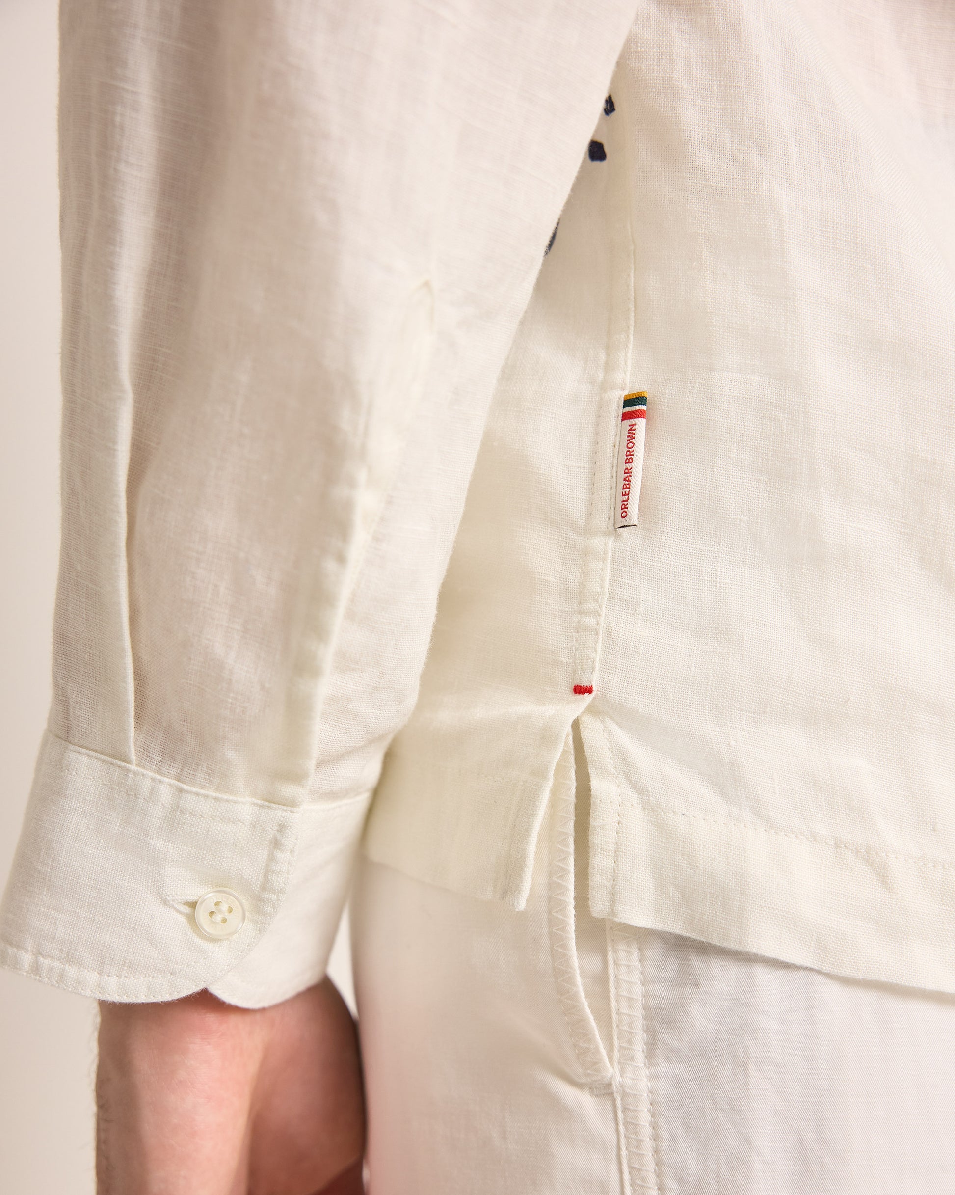 Close-up of a white shirt with a brand label on a plain background