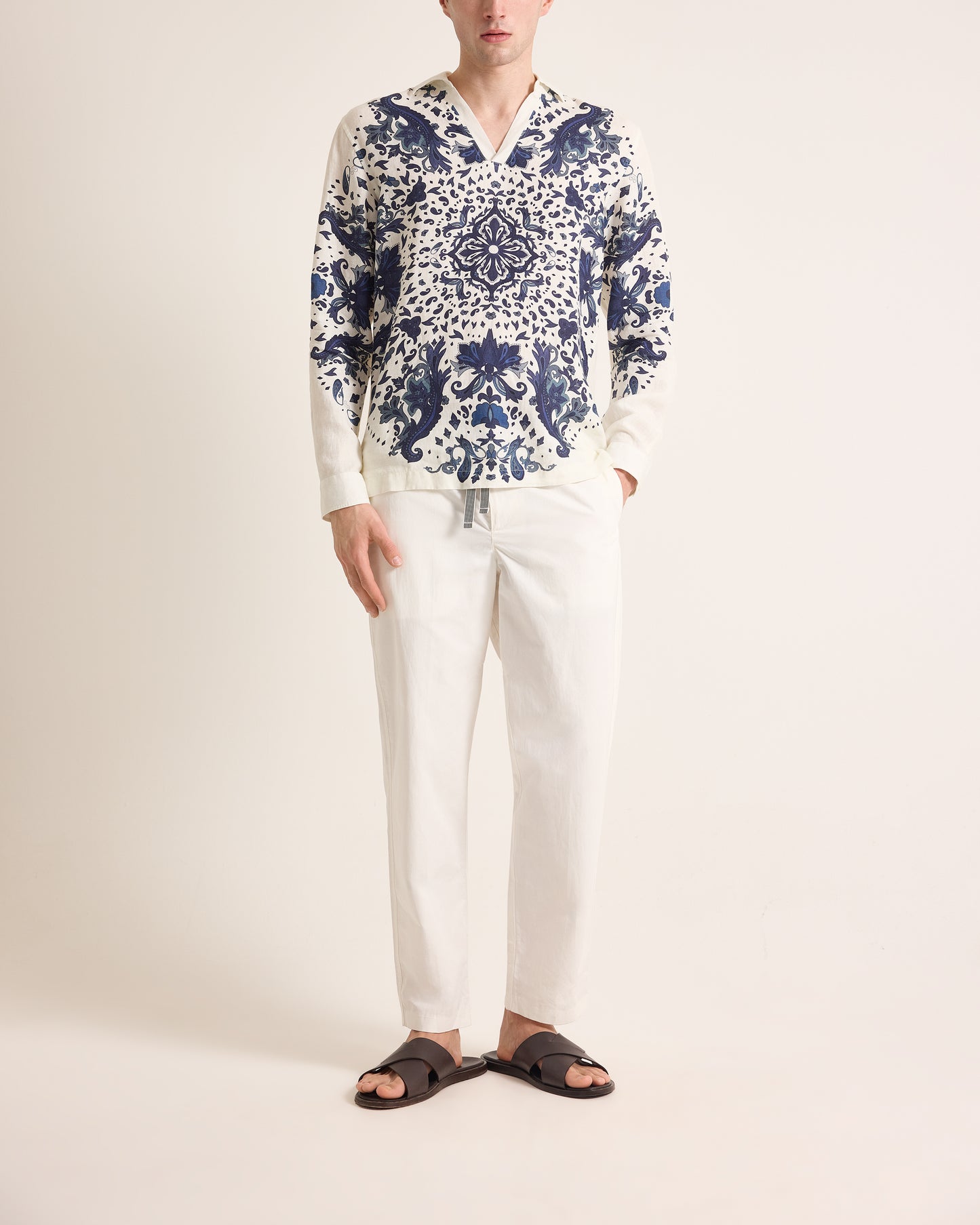Person wearing a blue and white patterned shirt with white pants on a plain background