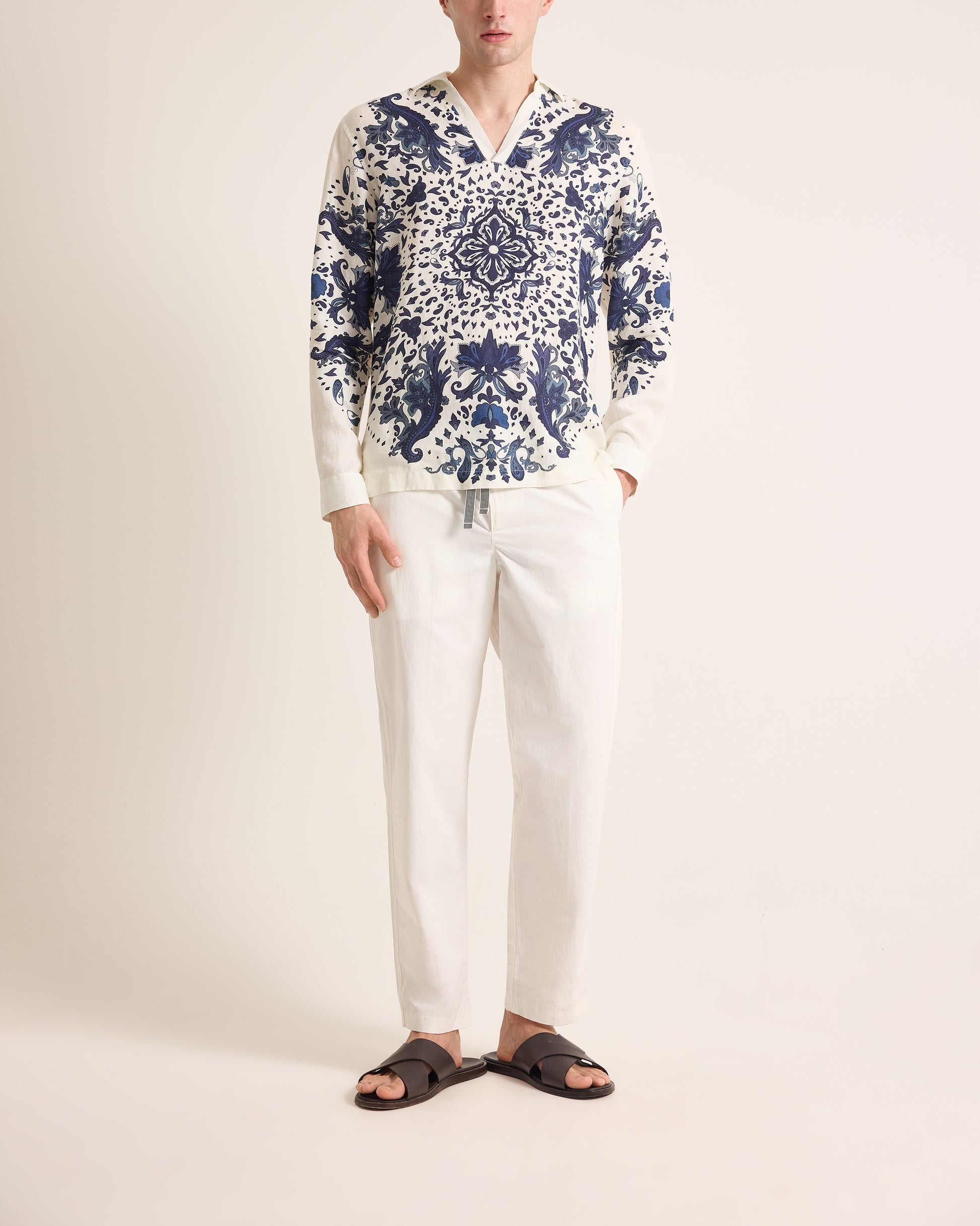 Person wearing a blue and white patterned shirt with white pants on a plain background