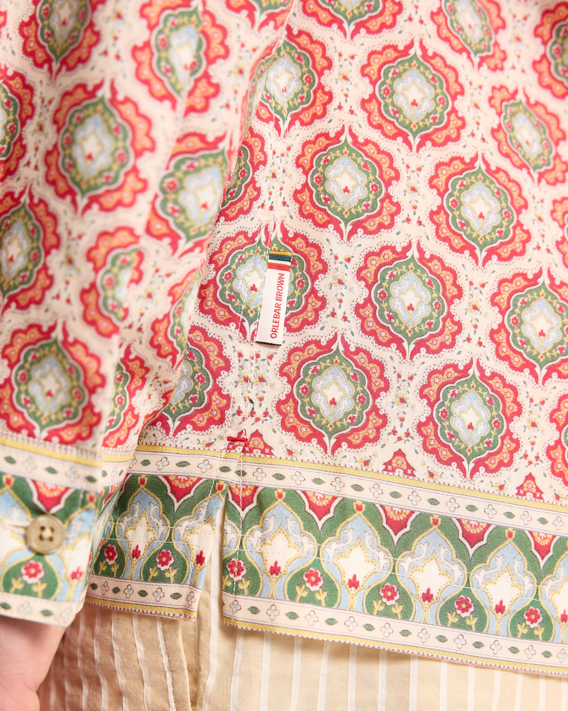 Close-up of a patterned fabric with red and green designs on a white background