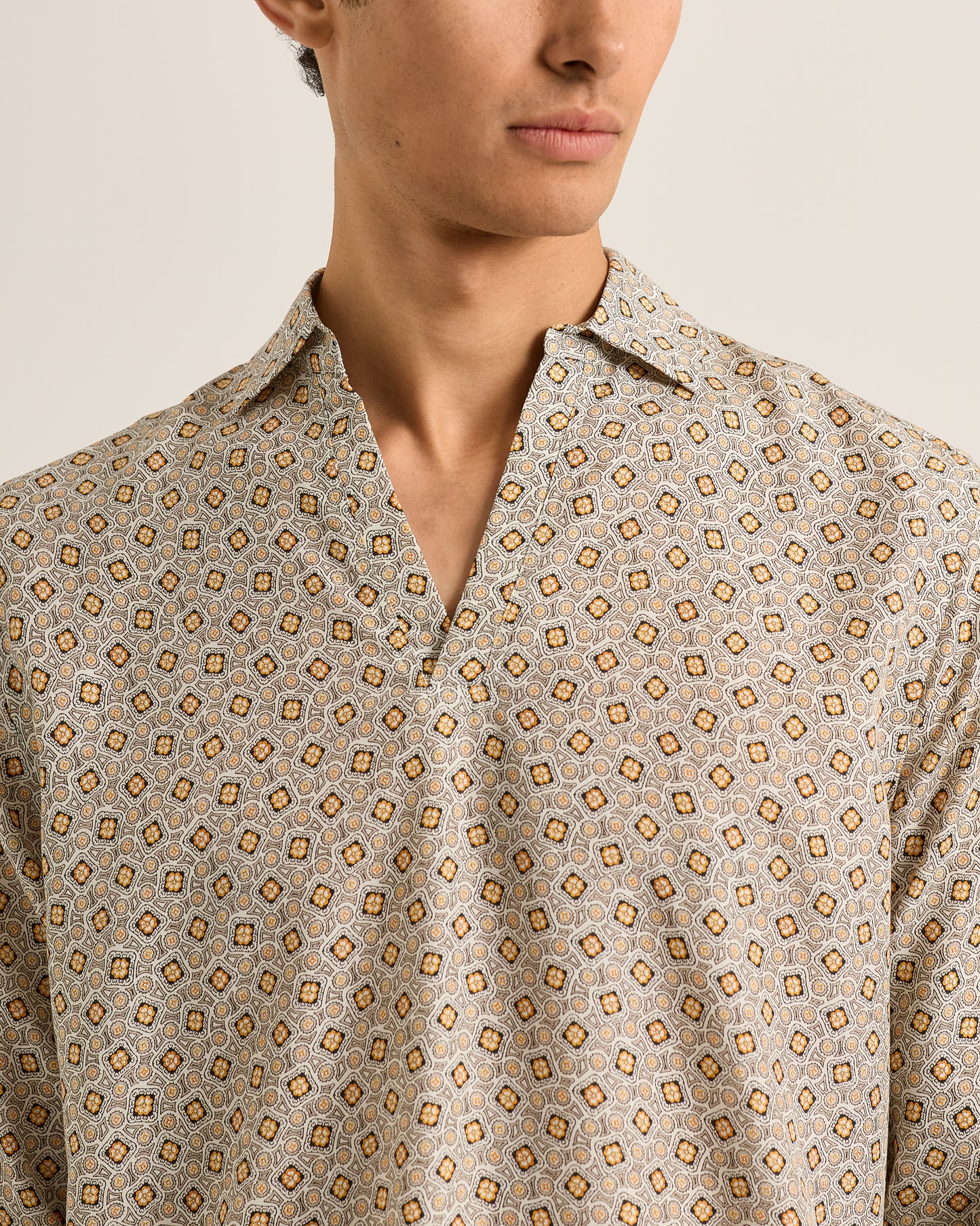 Close-up of a person wearing a patterned shirt with a neutral background