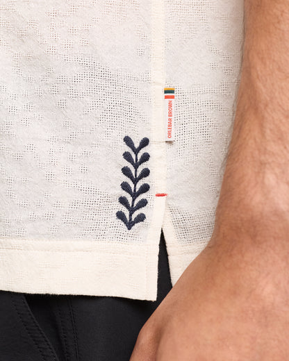 Close-up of embroidery detail on white shirt with branding label