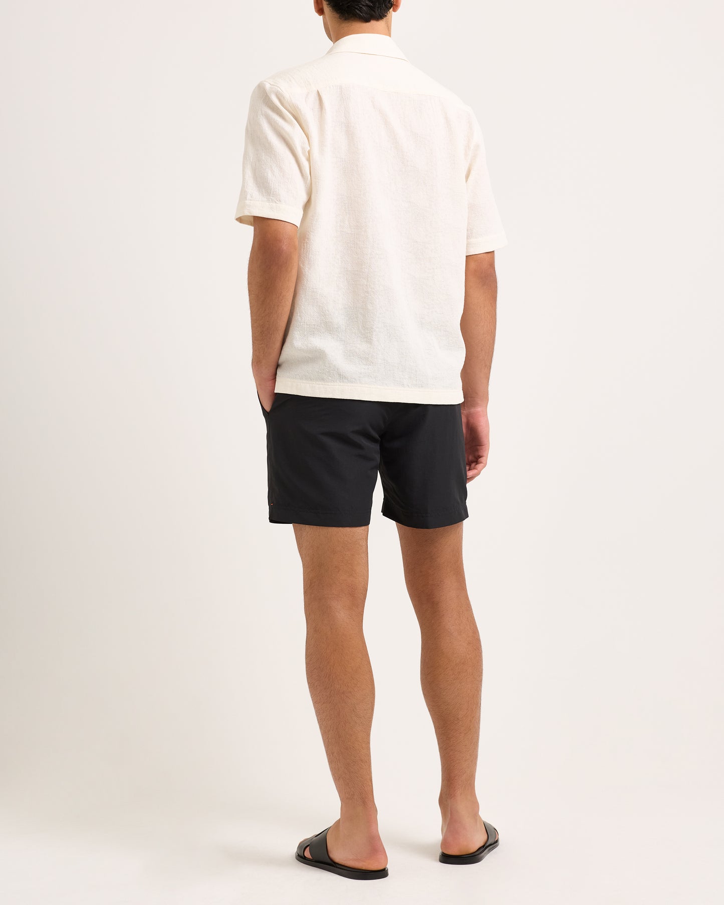 Person wearing a white shirt and black shorts on a plain background