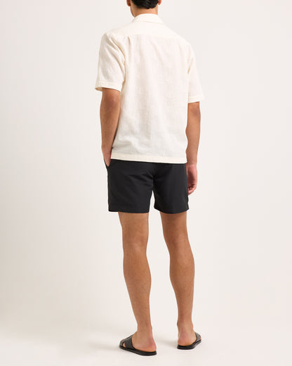 Person wearing a white shirt and black shorts on a plain background