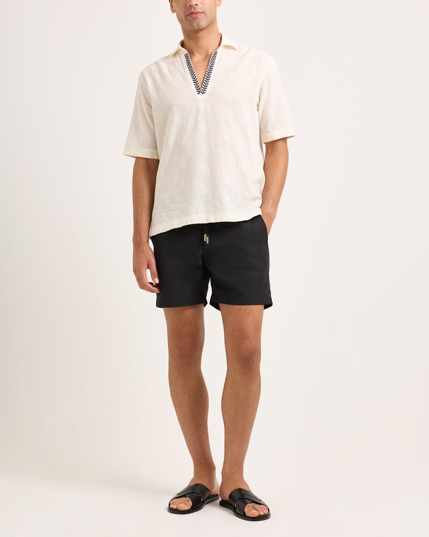 Man wearing a white shirt and black shorts on a plain background