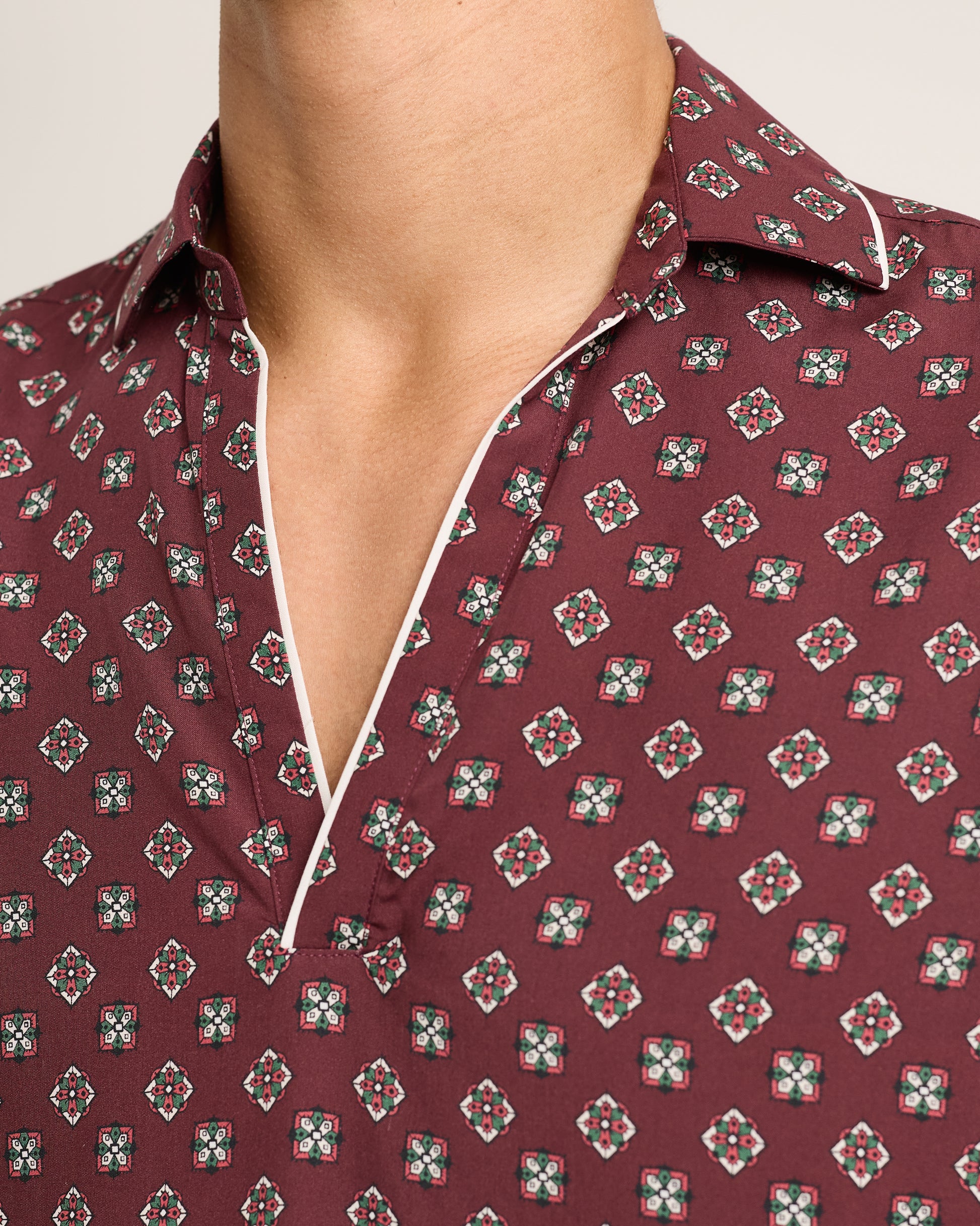 Close-up of a maroon shirt with a geometric pattern on a neutral background