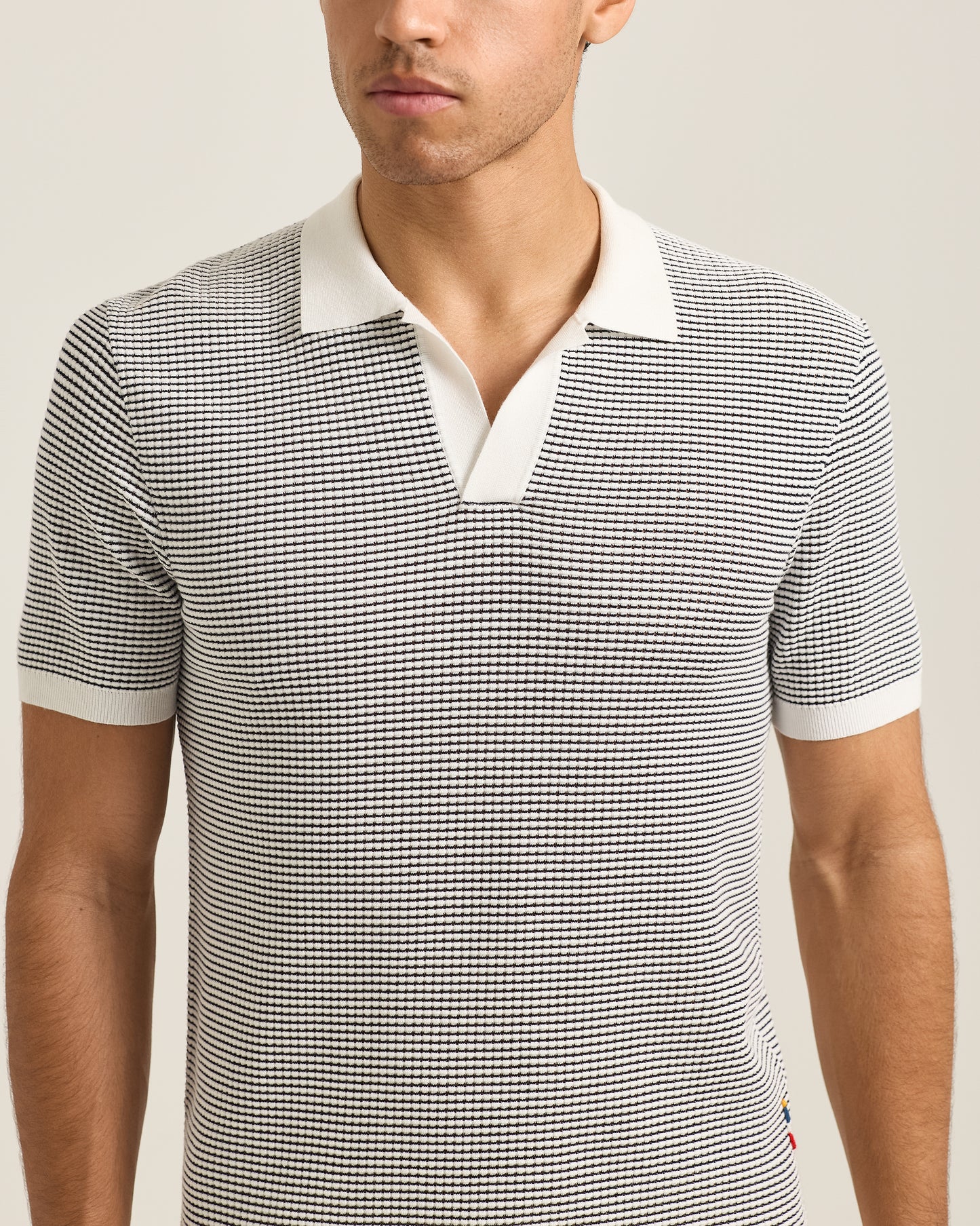 Closeup of man wearing black and grey polo shirt with white collar detail