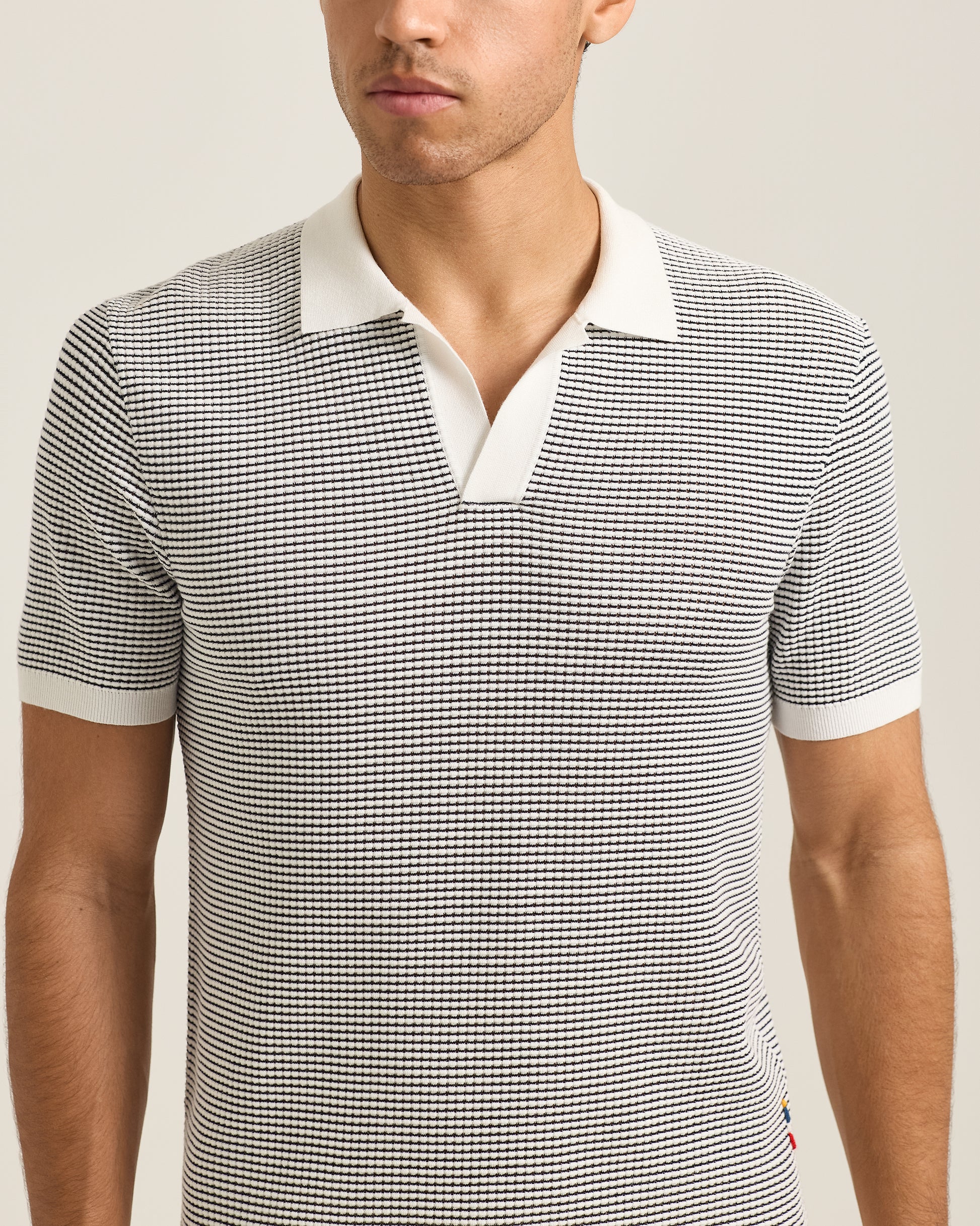 Closeup of man wearing black and grey polo shirt with white collar detail