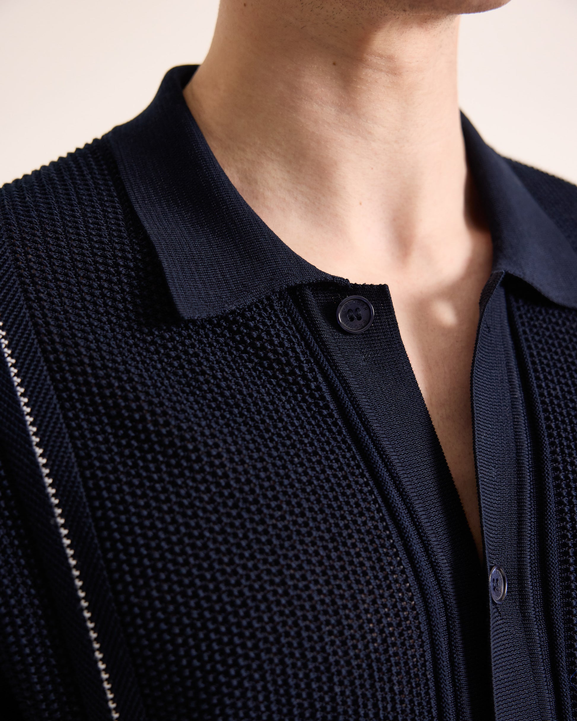 Close-up of a person wearing a dark blue textured cardigan.