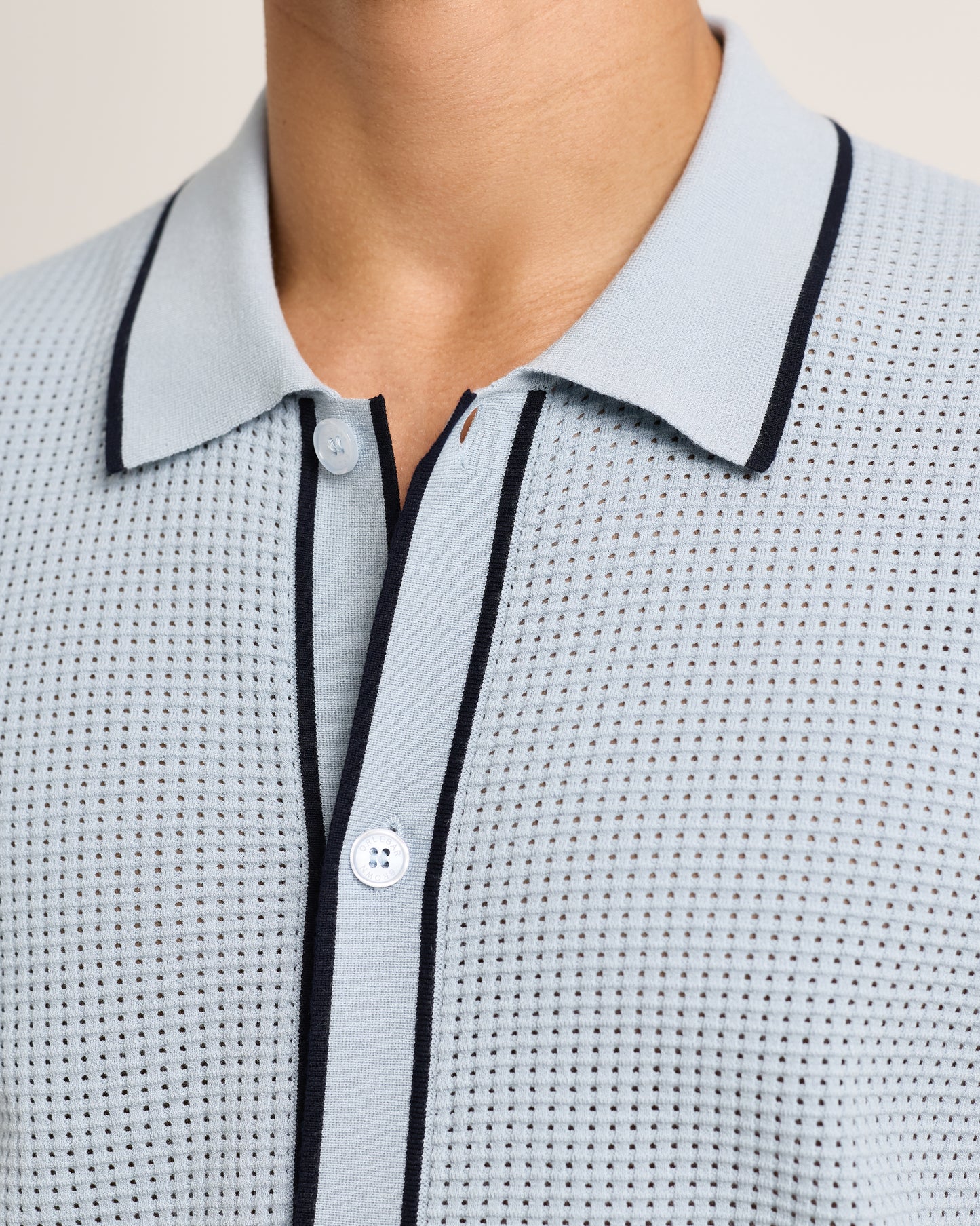 Light blue textured shirt with black trim on a neutral background