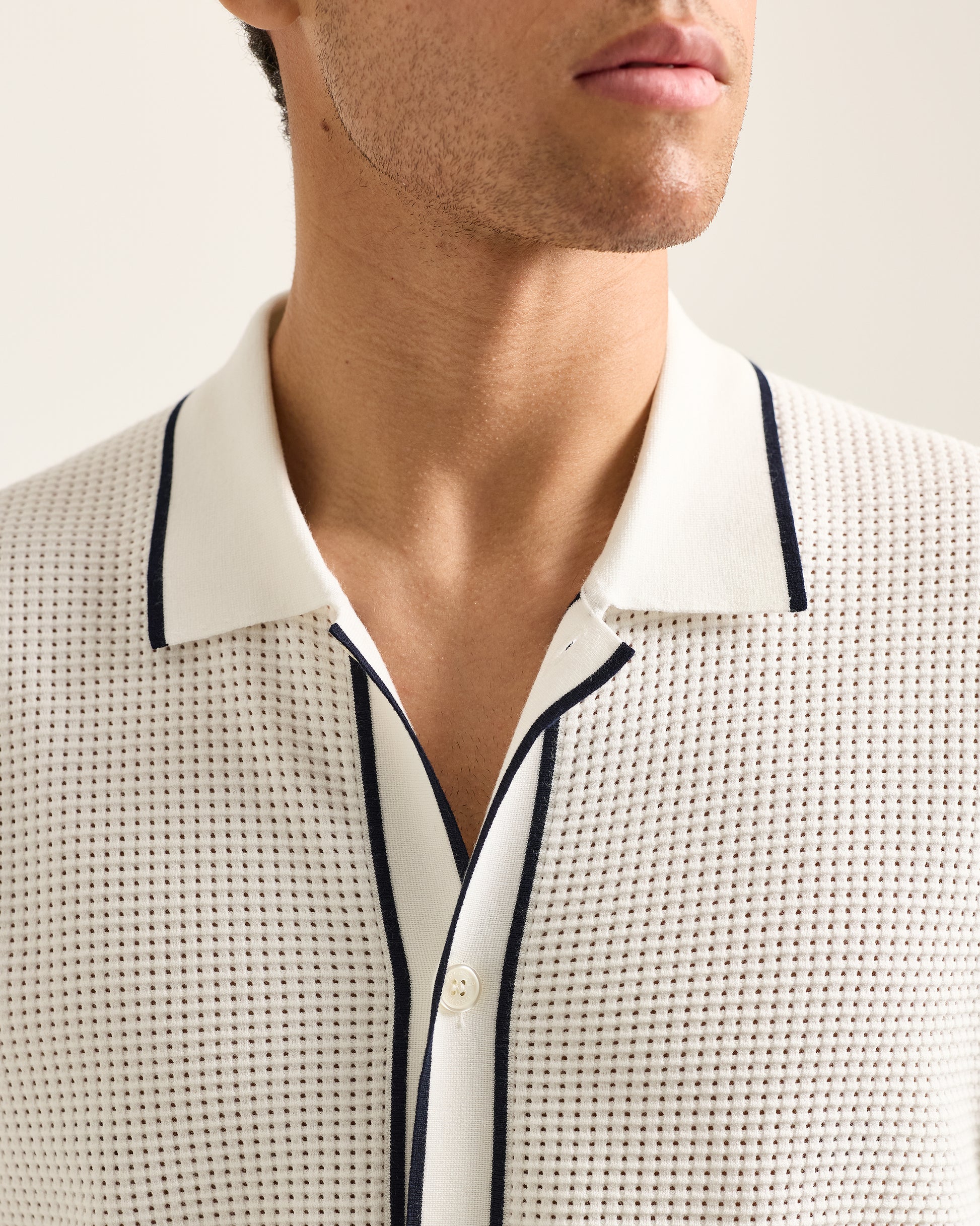 Close-up of a person wearing a textured shirt with a collar and trim details.