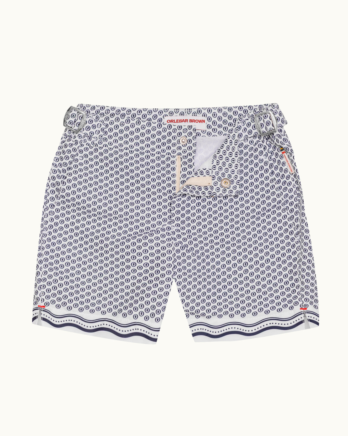 A pair of swimshorts featuring a navy blue and white geometric pattern, with a decorative wavy navy and white border along the hem and a matching patterned drawstring waist.