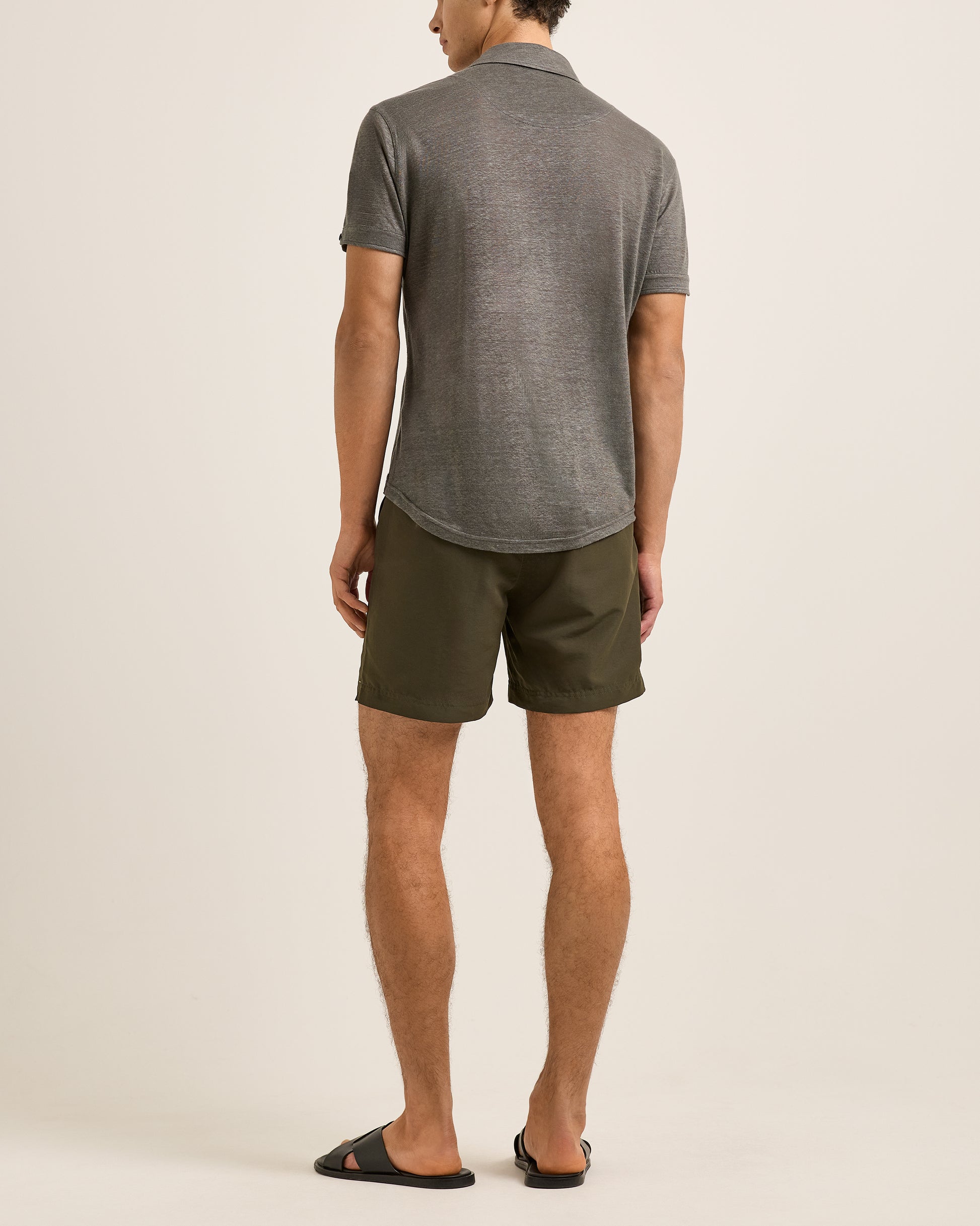 Man wearing a gray polo shirt and green shorts on a beige background