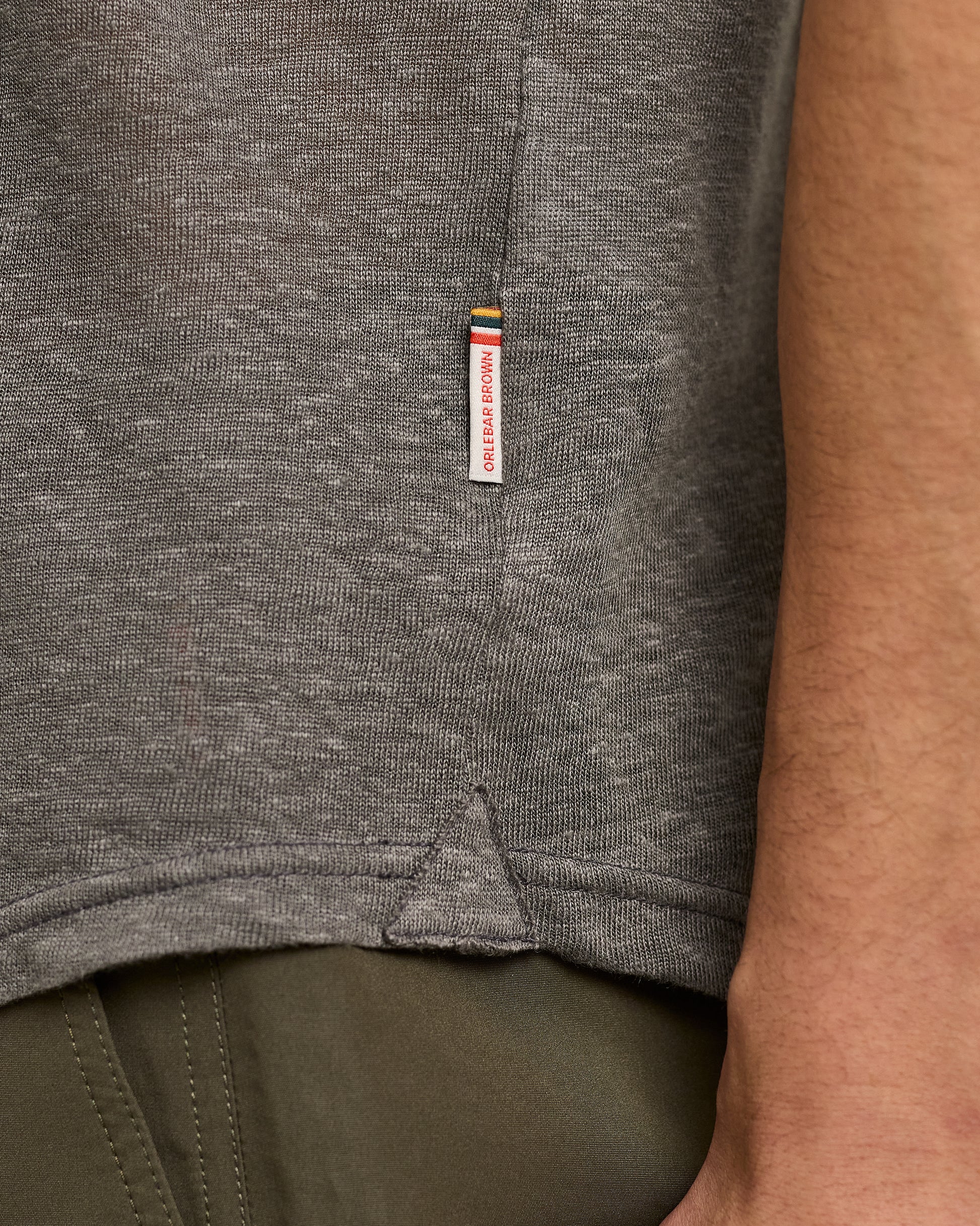 Close-up of a gray shirt with a brand label on a person wearing it.